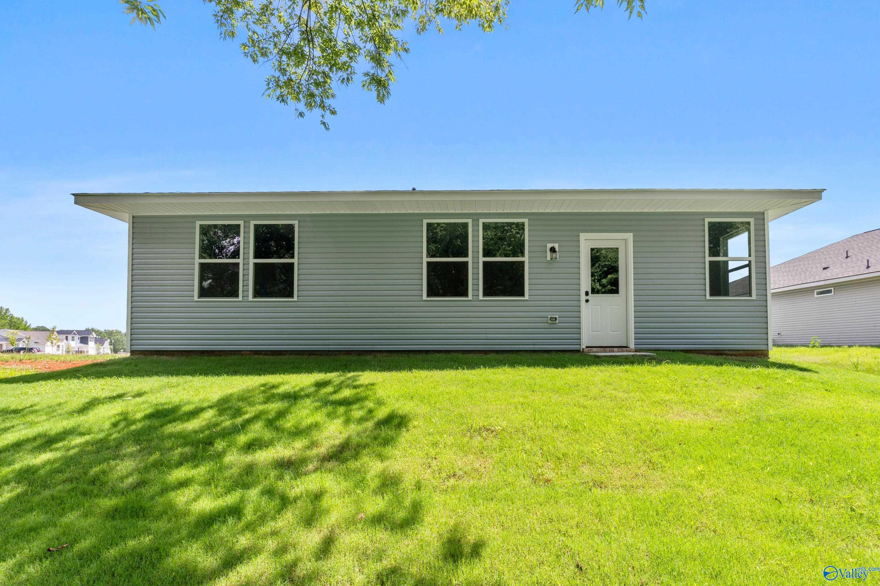 Back view of single-story gray-sided 3-bedroom home with windows, door, and green lawn in Forest Glen, Hazel Green, Alabama