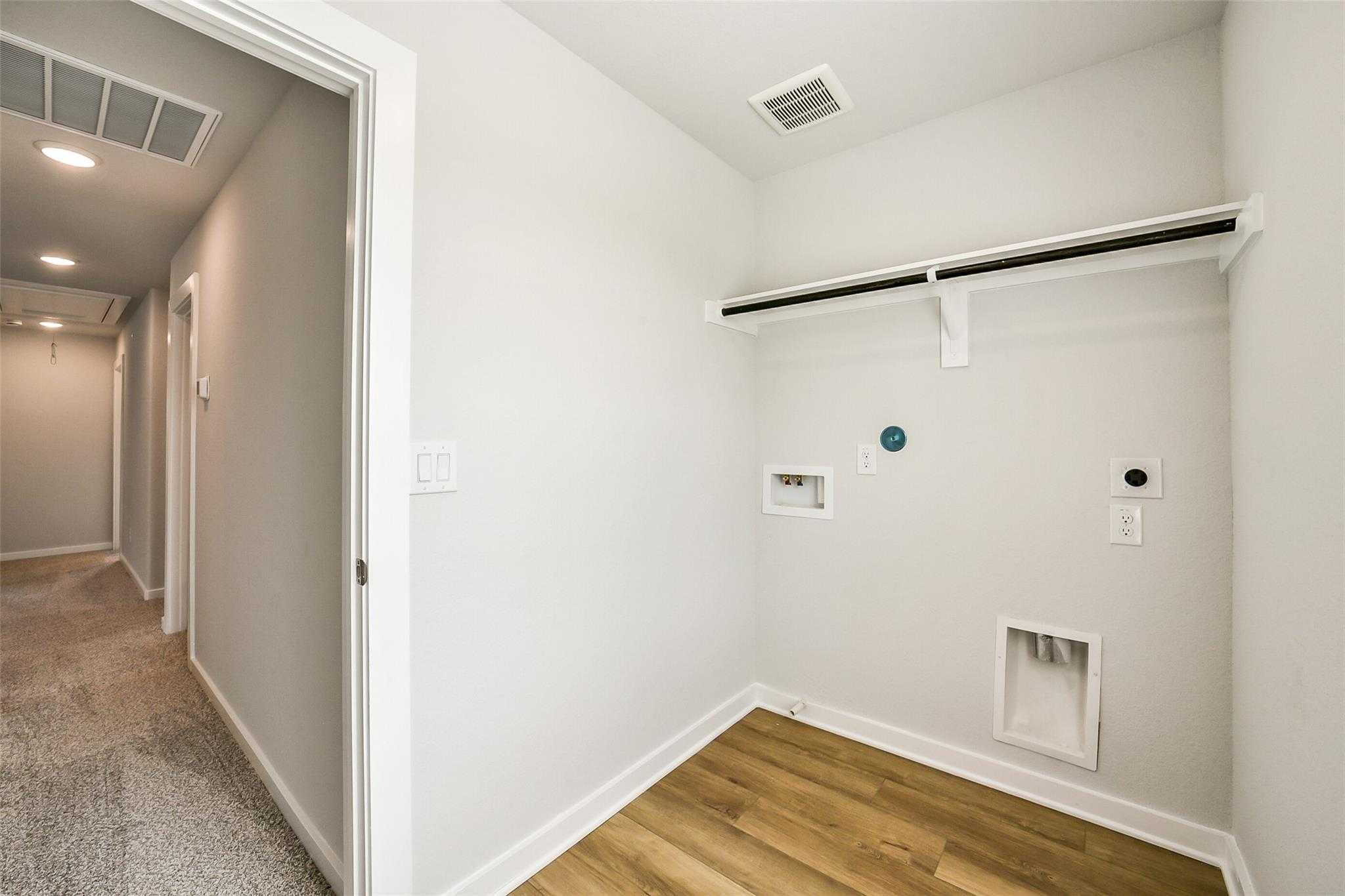 Modern laundry room with built-in shelves, washer/dryer hookups, and utility sink in Davidson Homes The Trinity F, Magnolia, Texas