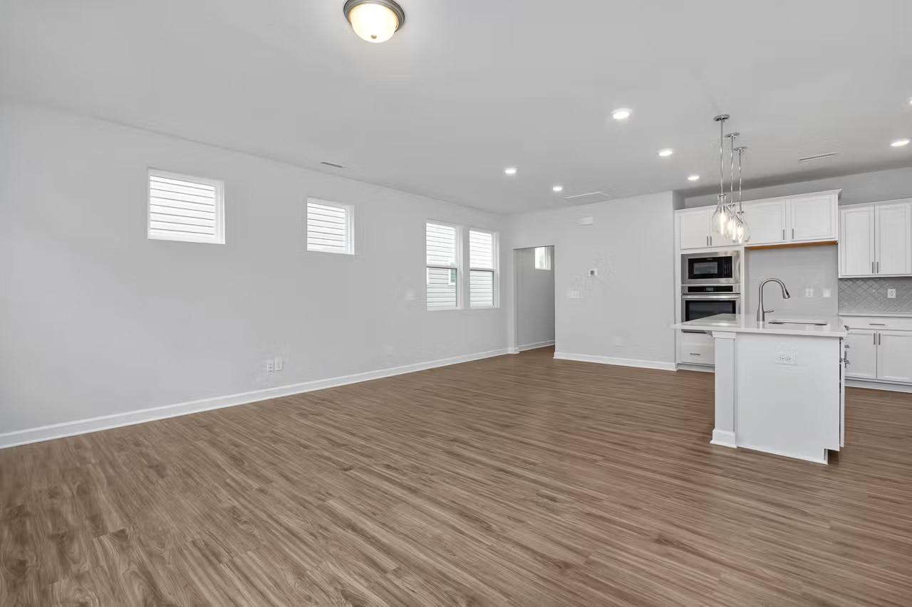 Modern open-concept kitchen with white island, stainless steel appliances, and hardwood floors in Davidson Homes The Durham C, Wylie, Texas