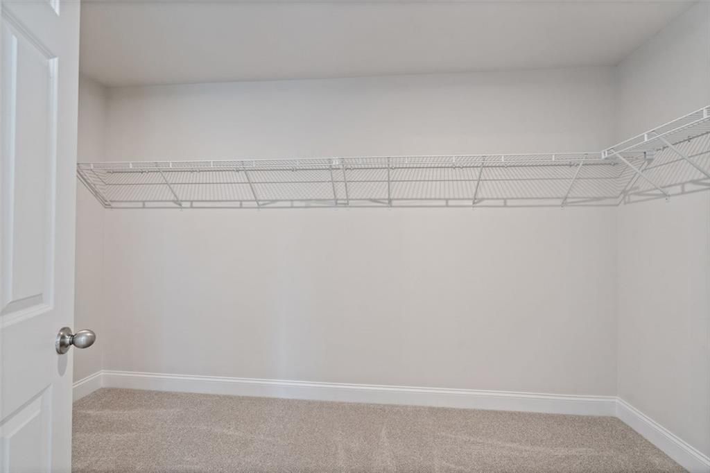 Spacious walk-in closet with white wire shelving in master suite of Davidson Homes The Hickory B at Wehunt Meadows, Hoschton, Georgia