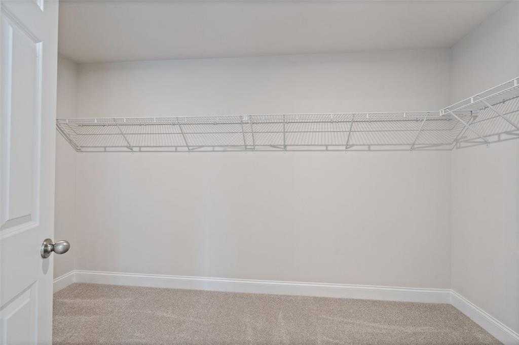 Spacious walk-in closet with white wire shelving in master suite of Davidson Homes The Hickory B at Wehunt Meadows, Hoschton, Georgia