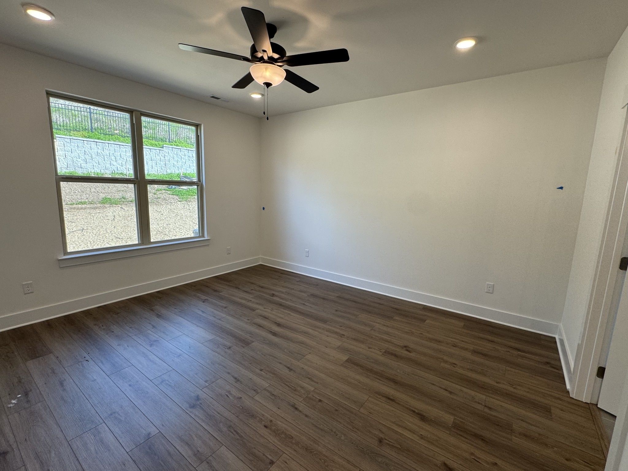 Spacious bedroom featuring hardwood floors, ceiling fan, recessed lights, and large windows in Davidson Homes The Ridgeport C, Gallatin, Tennessee