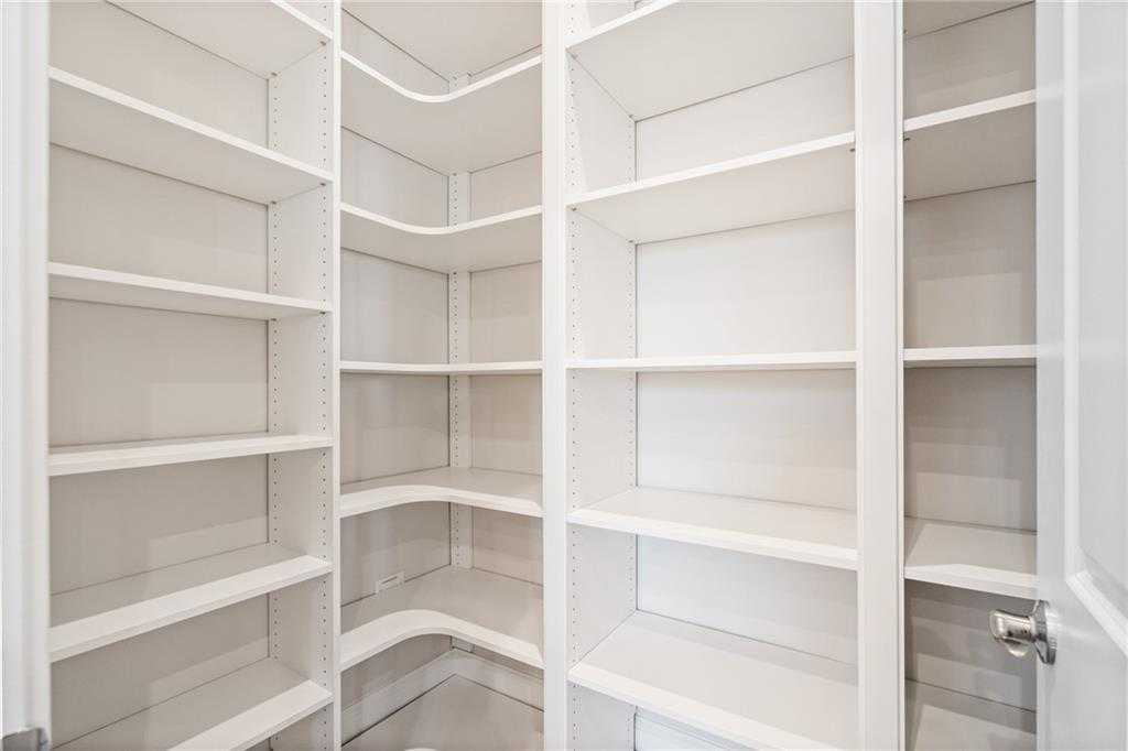 Spacious corner walk-in closet with white wooden shelving in master suite, Davidson Homes The Arlington A, East Cobb, Georgia