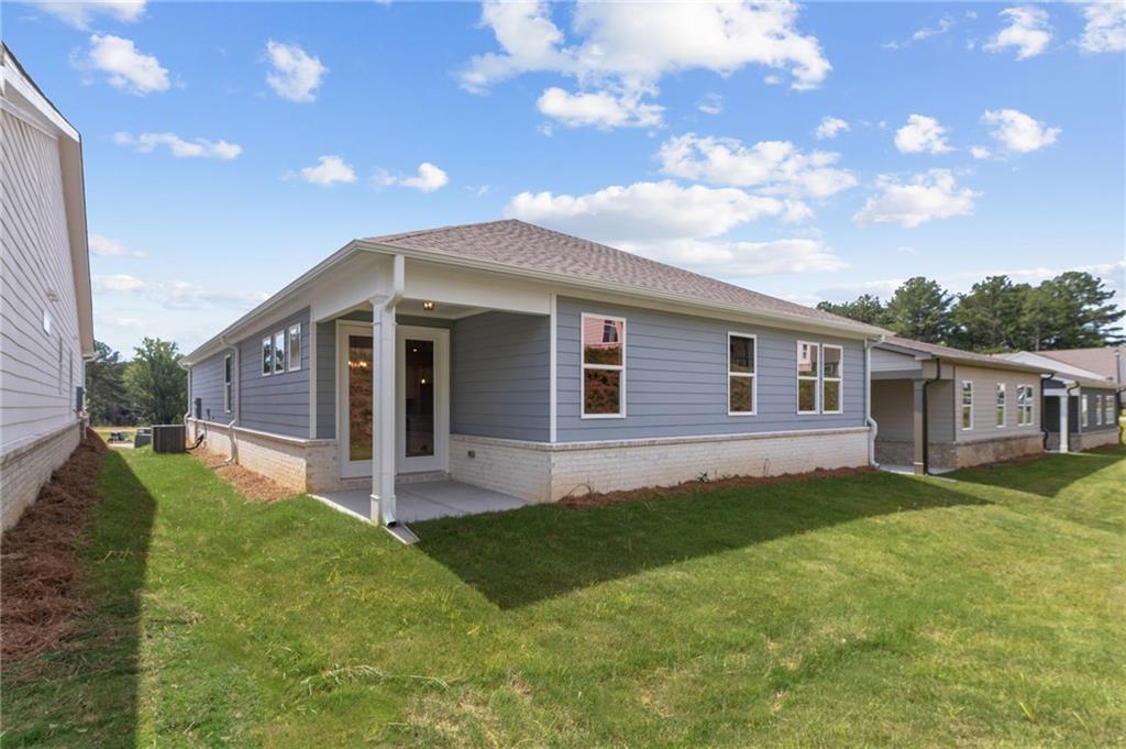 Modern single-story gray home with covered porch, 2-car garage, and lush lawn in Kelly Preserve, Loganville, Georgia