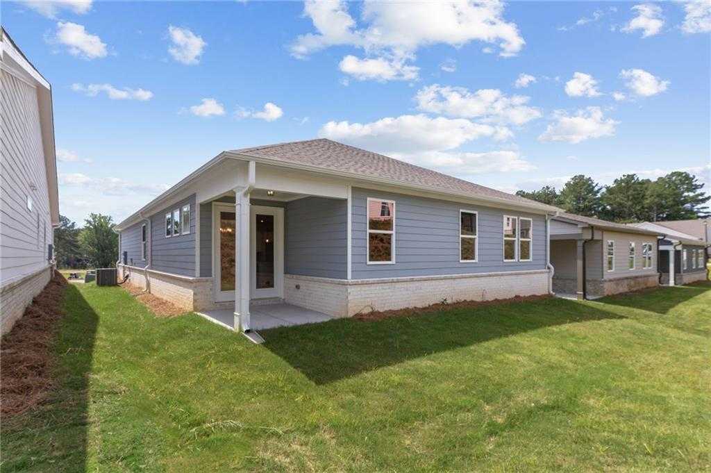 Modern single-story home exterior with gray siding, covered porch, and lush green lawn in Kelly Preserve, Loganville, Georgia