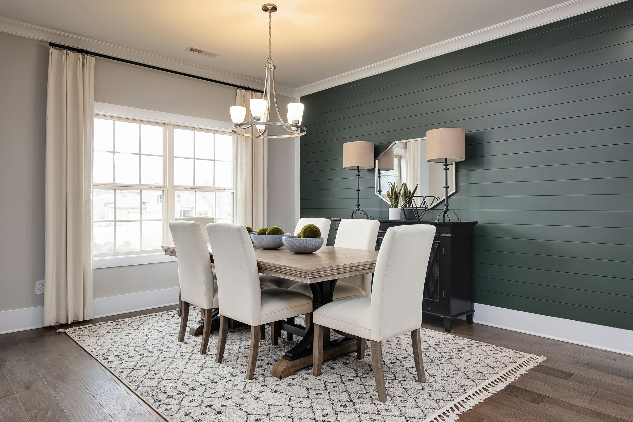 Spacious dining room in Chimney Creek Hampton Cove Alabama with farmhouse table white chairs green shiplap walls chandelier