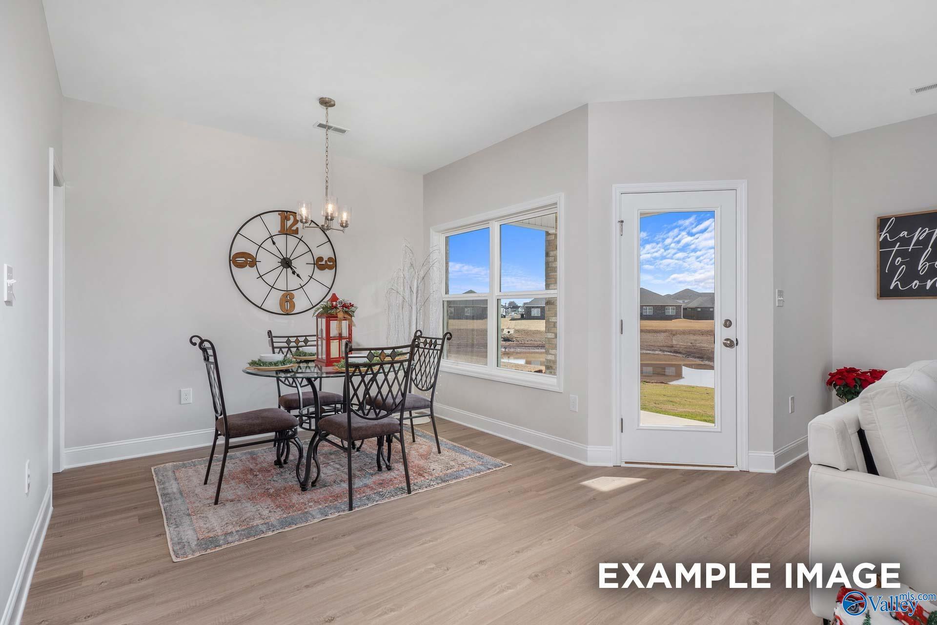 Elegant dining room with chandelier, round table, upholstered chairs, and backyard view in Davidson Homes The Daphne D, Meridianville, Alabama