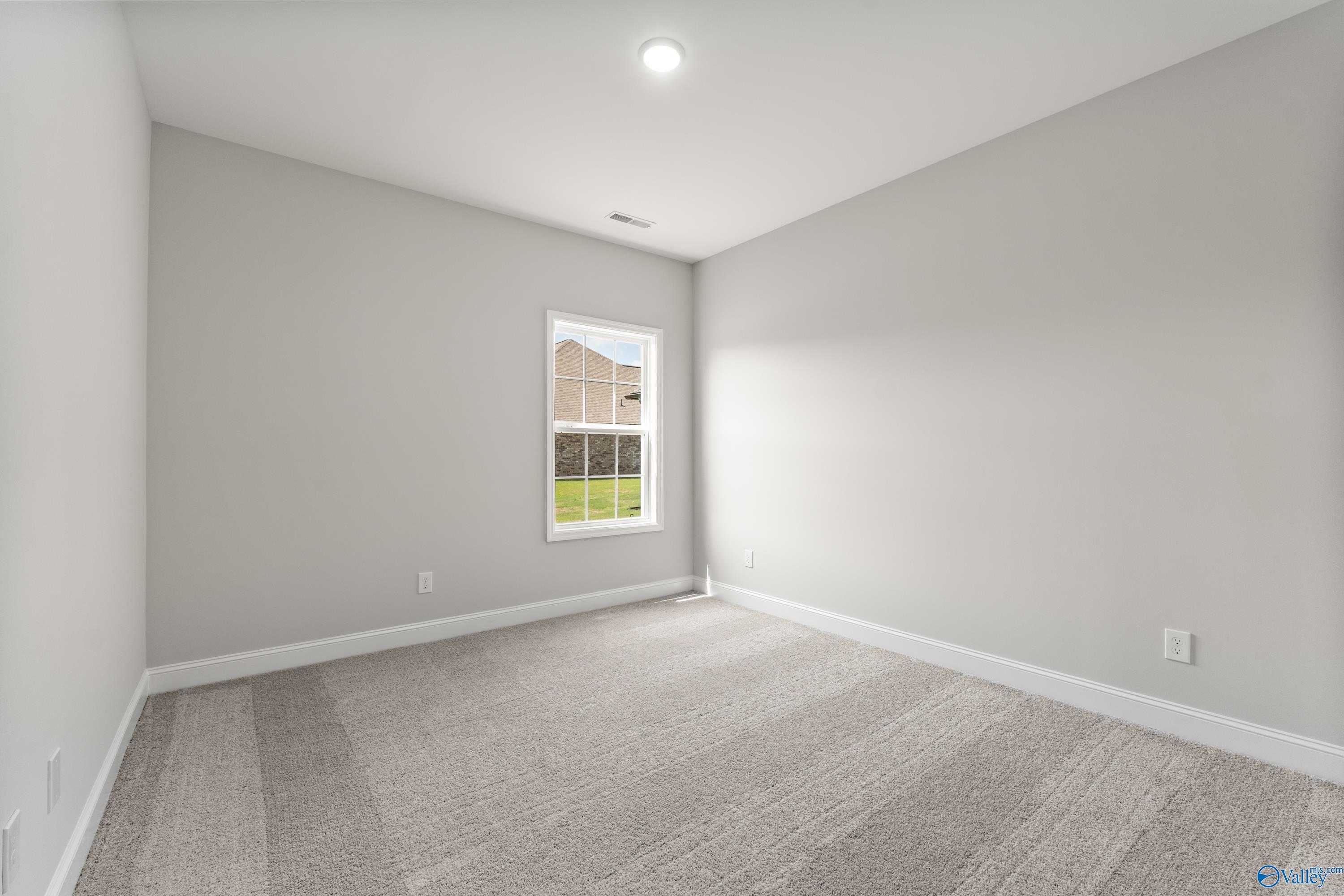 Bright secondary bedroom with light gray walls, carpet floor, and window view in The Madison A, Davidson Homes, Toney, Alabama
