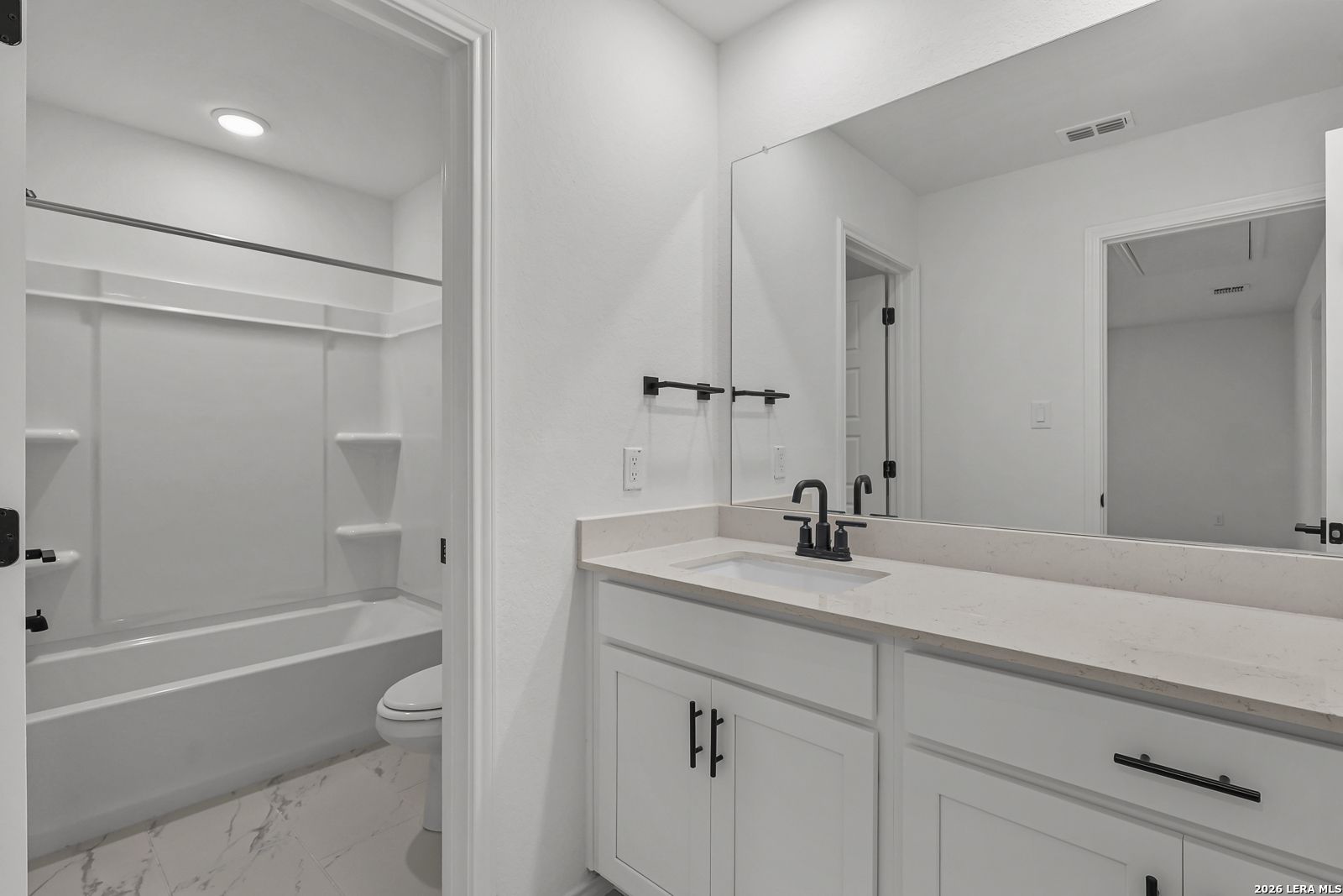 Modern bathroom with white vanity, quartz countertops, and tub-shower combo in The Gillian C by Davidson Homes, San Antonio.