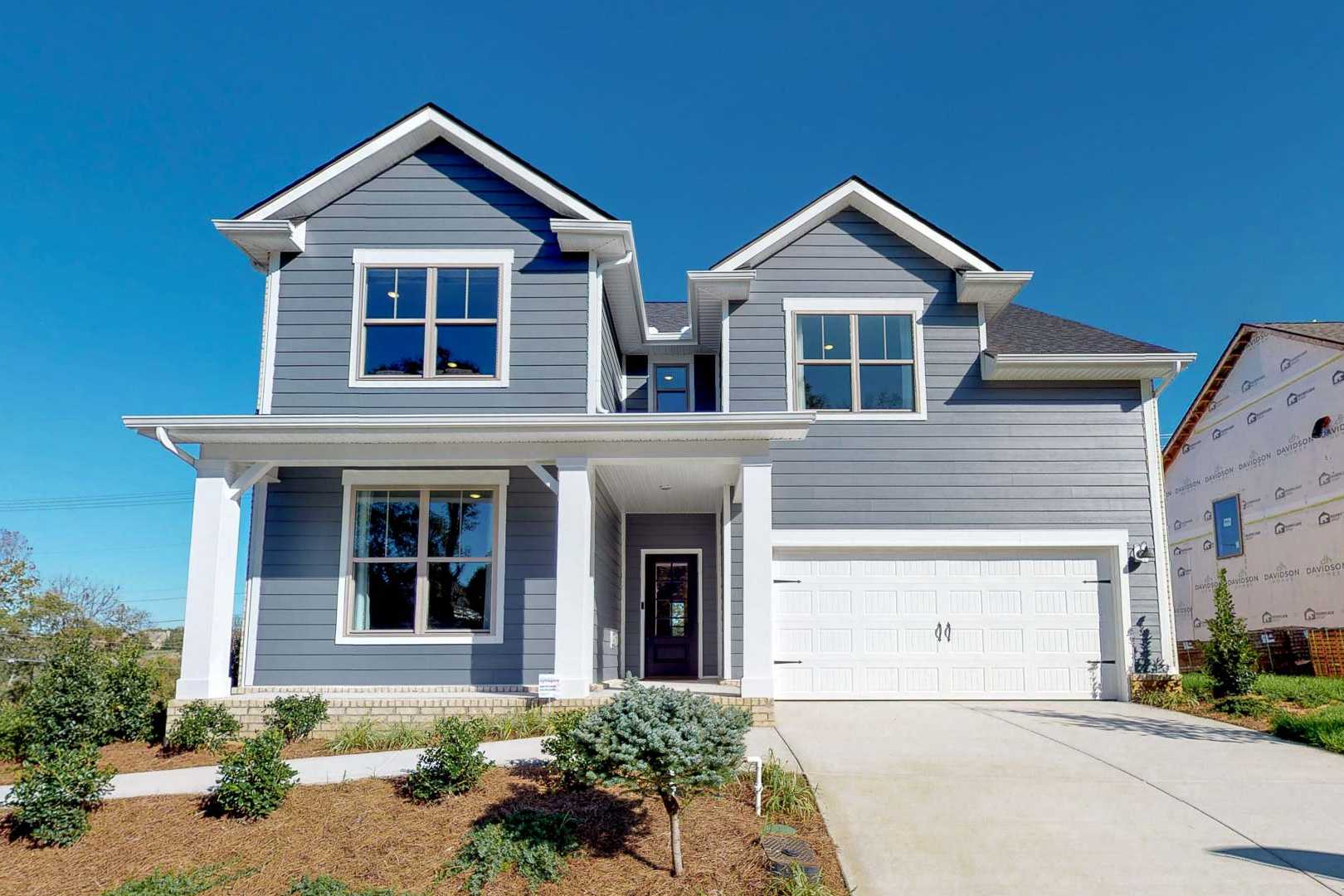 Contemporary gray two-story home exterior at Liberty Creek in Gallatin Tennessee with covered porch, columns, and landscaped yard