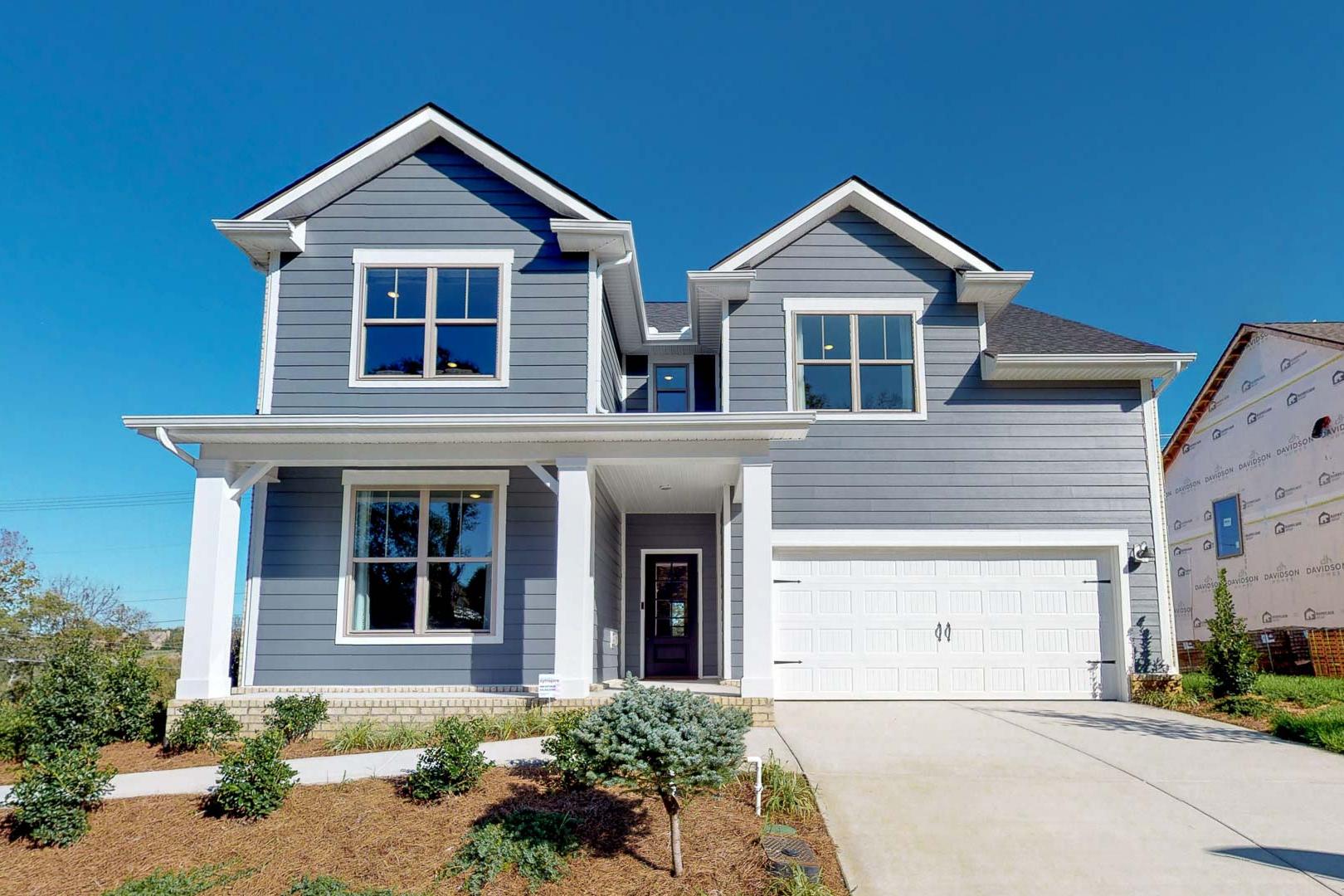 Contemporary gray two-story home exterior at Liberty Creek in Gallatin Tennessee with covered porch, columns, and landscaped yard