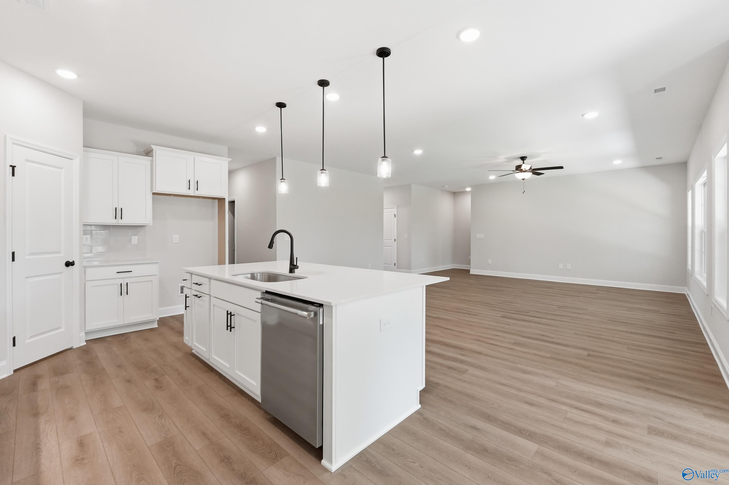 Open-concept kitchen with white cabinets and island in The Rockford B floor plan at The Meadows, Athens, Alabama.