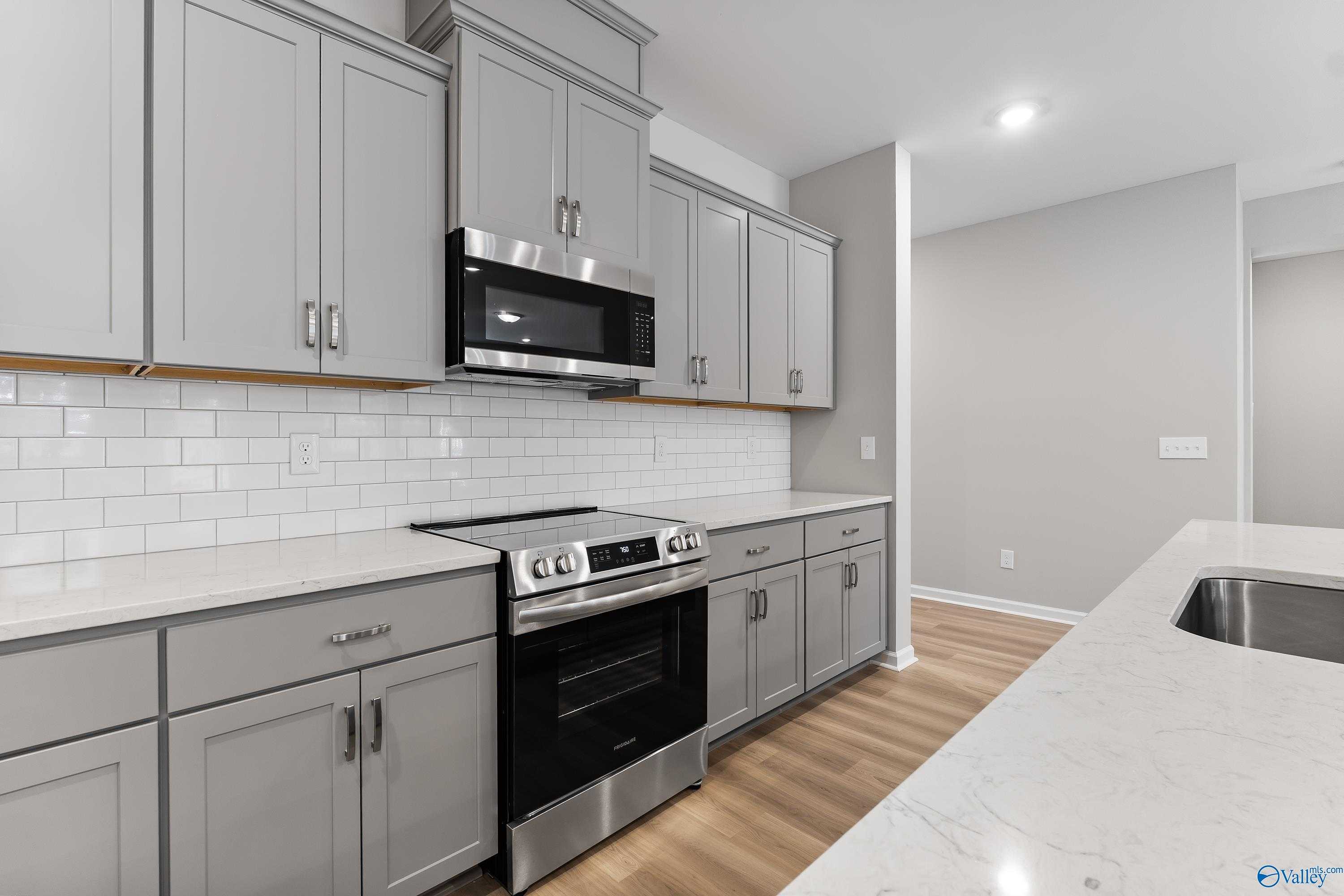 Modern kitchen featuring gray shaker cabinets, subway tile backsplash, quartz counters, stainless appliances in Evermore Homes The Grace, Madison AL