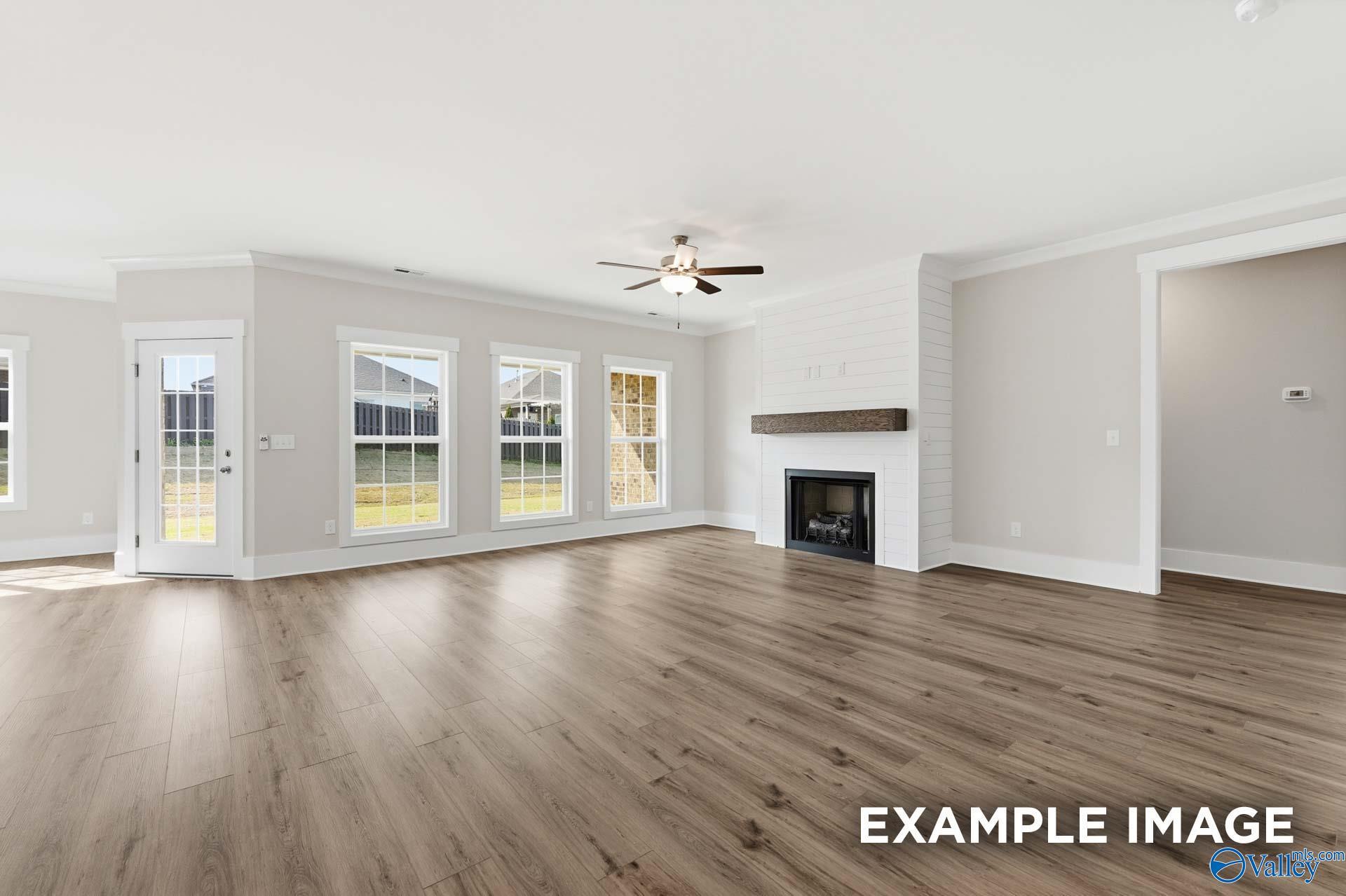Spacious living room with shiplap fireplace and wood floors in The Harrison floor plan, Briercreek, Meridianville, Alabama.