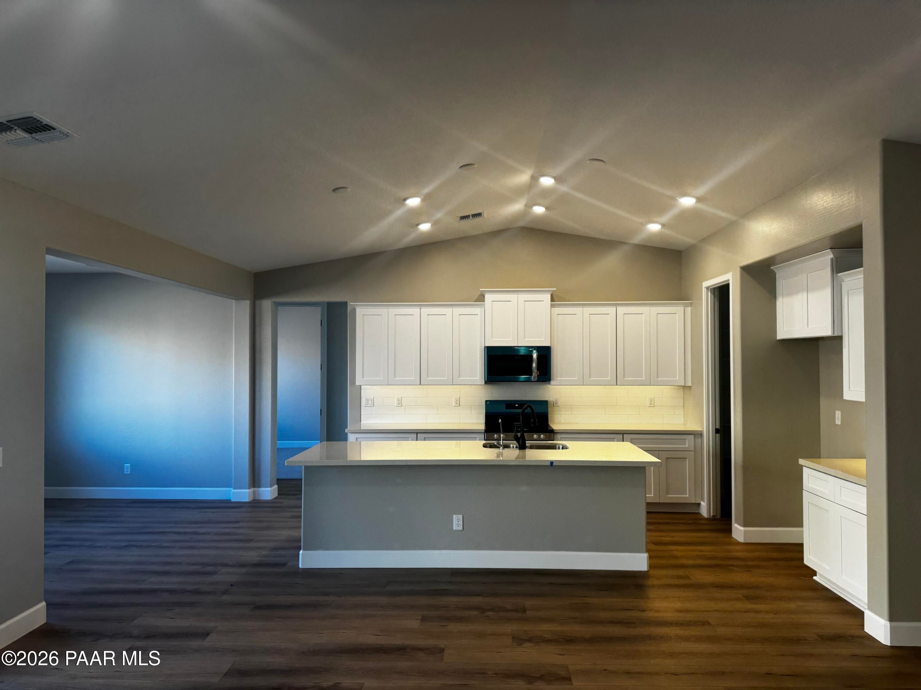Modern open-concept kitchen featuring white shaker cabinets, stainless steel appliances, and gray island in Evermore Homes The Monarch B, Prescott Valley, AZ