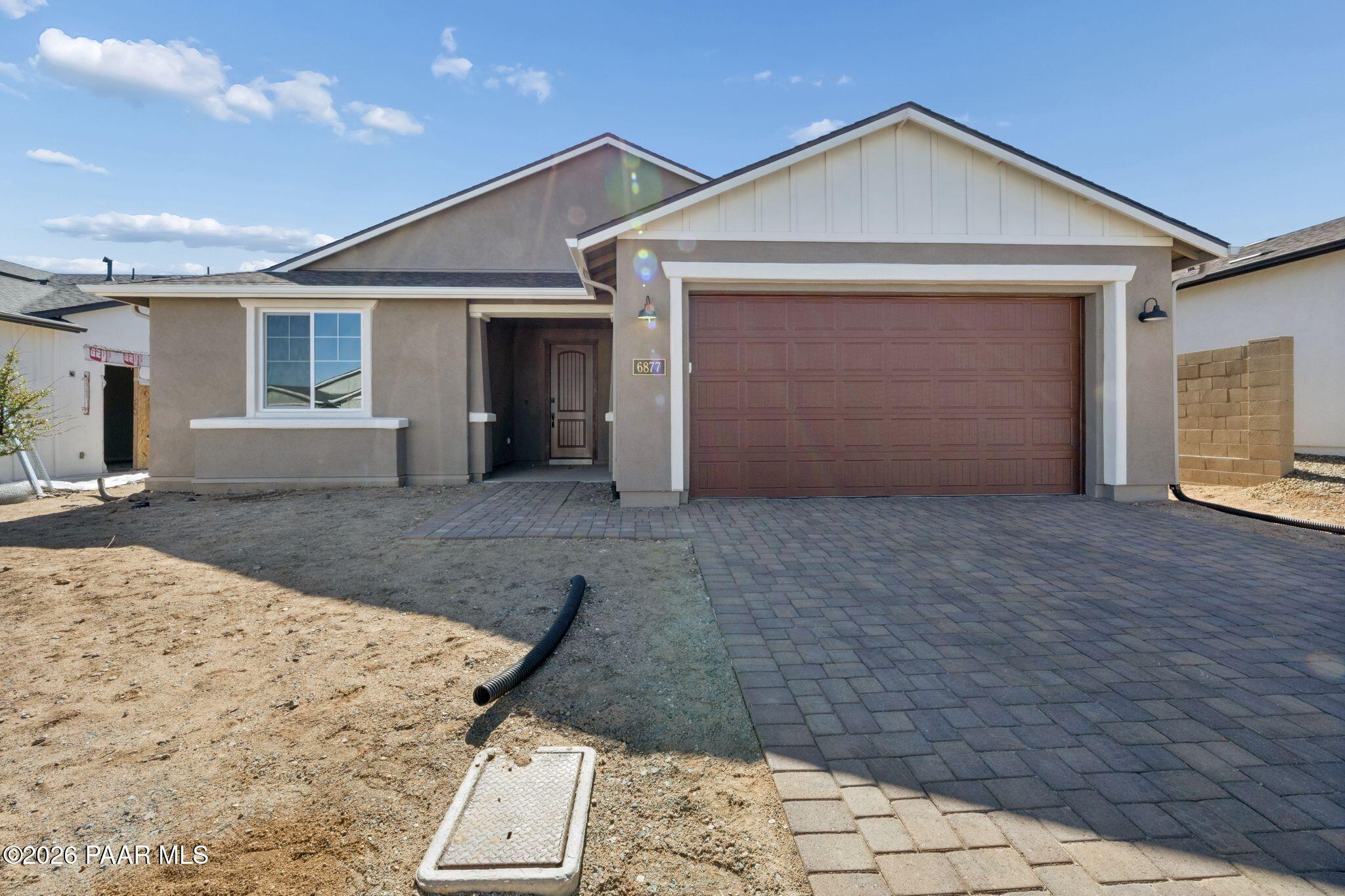 Modern beige stucco single-story home with 3-car garage and paver driveway in Westwood, Prescott, Arizona by Davidson Homes Durango II B