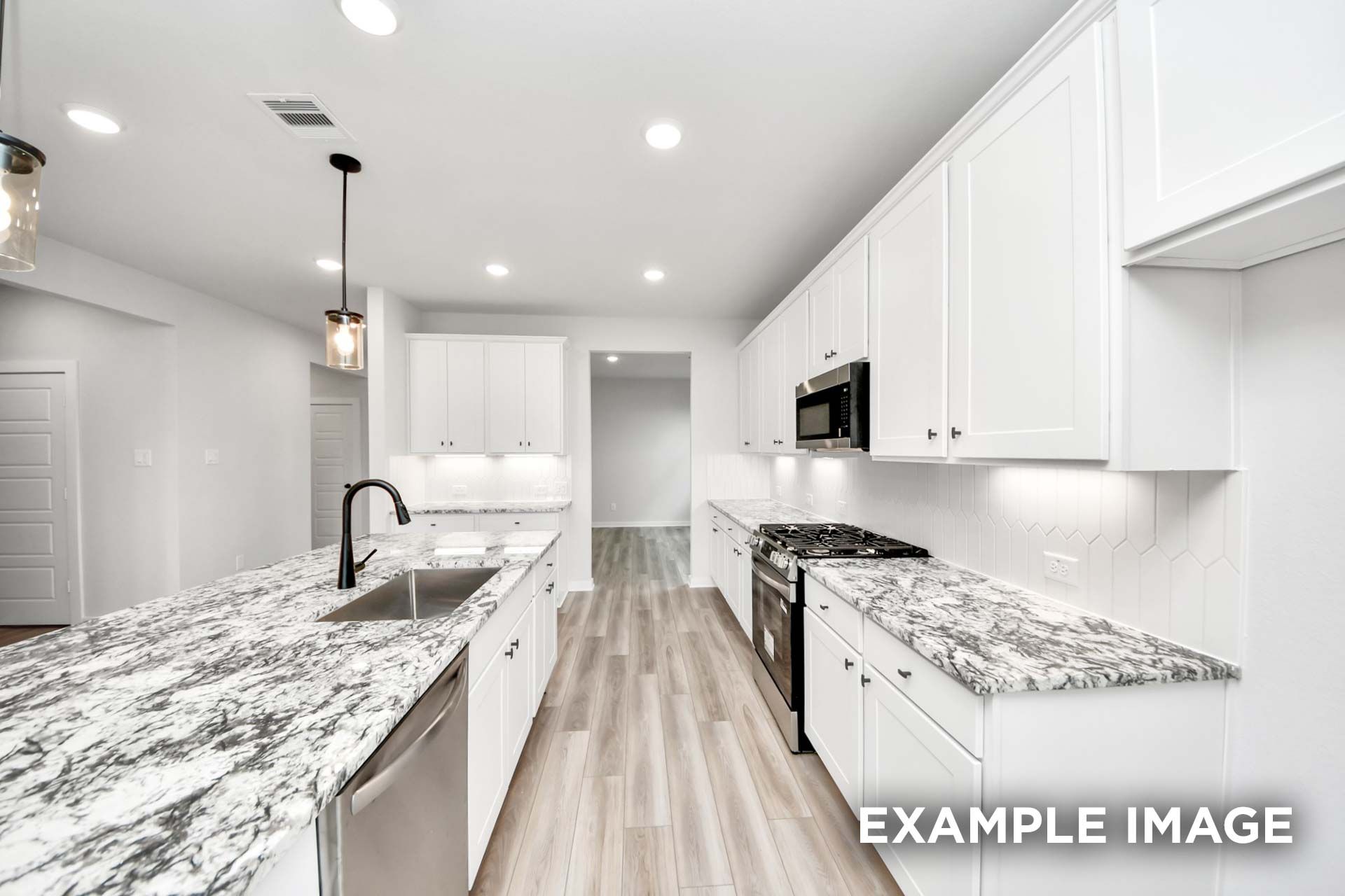 Modern kitchen in The Sorrento featuring white shaker cabinets, granite countertops, and a spacious center island.