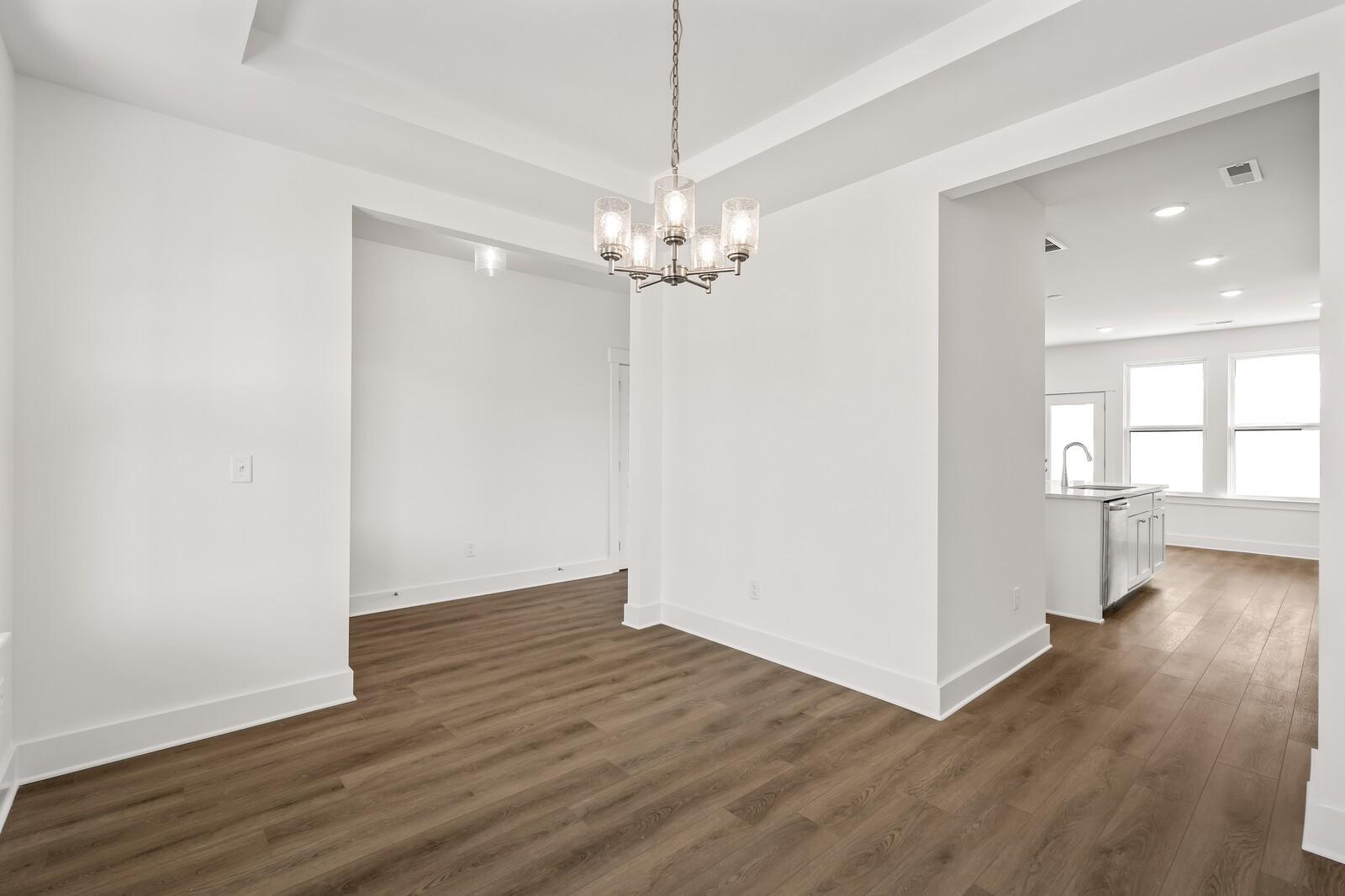 Bright dining room with modern chandelier, hardwood floors, open to white kitchen in The Willow D by Davidson Homes, Mt. Juliet, TN