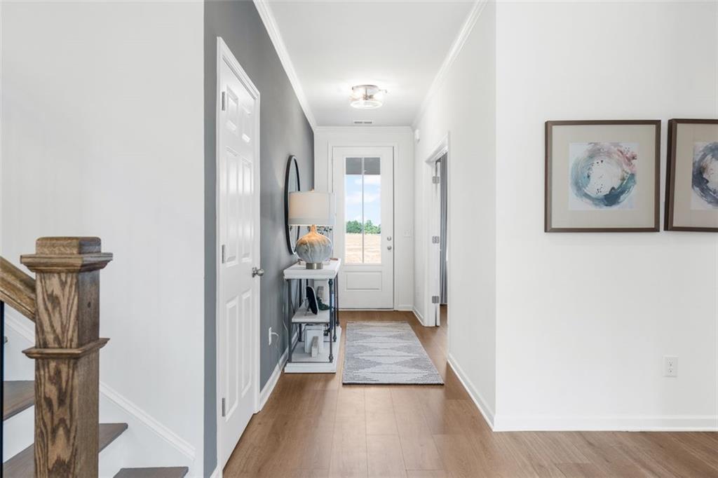 Bright entry hallway with oak staircase, console table, mirror, and abstract art in 5-bedroom Davidson Homes, Hoschton, GA