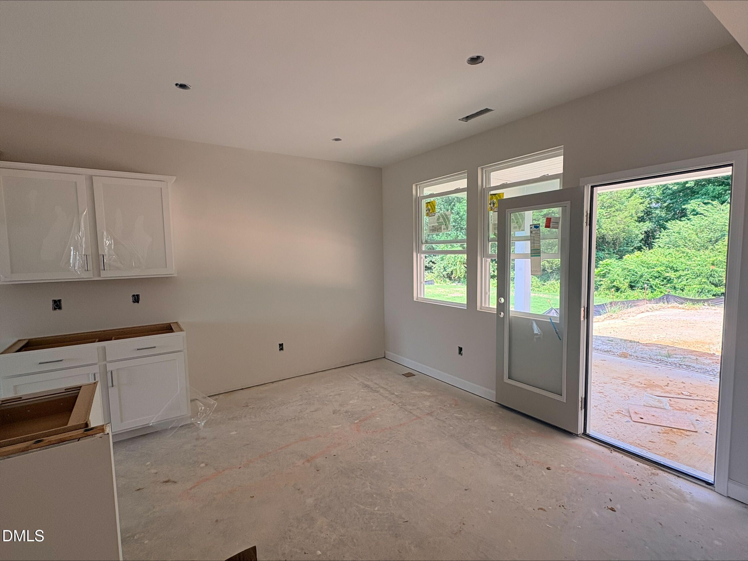 Unfinished kitchen area with white cabinets and glass door access to the backyard in Woodland Crossing, Zebulon home.