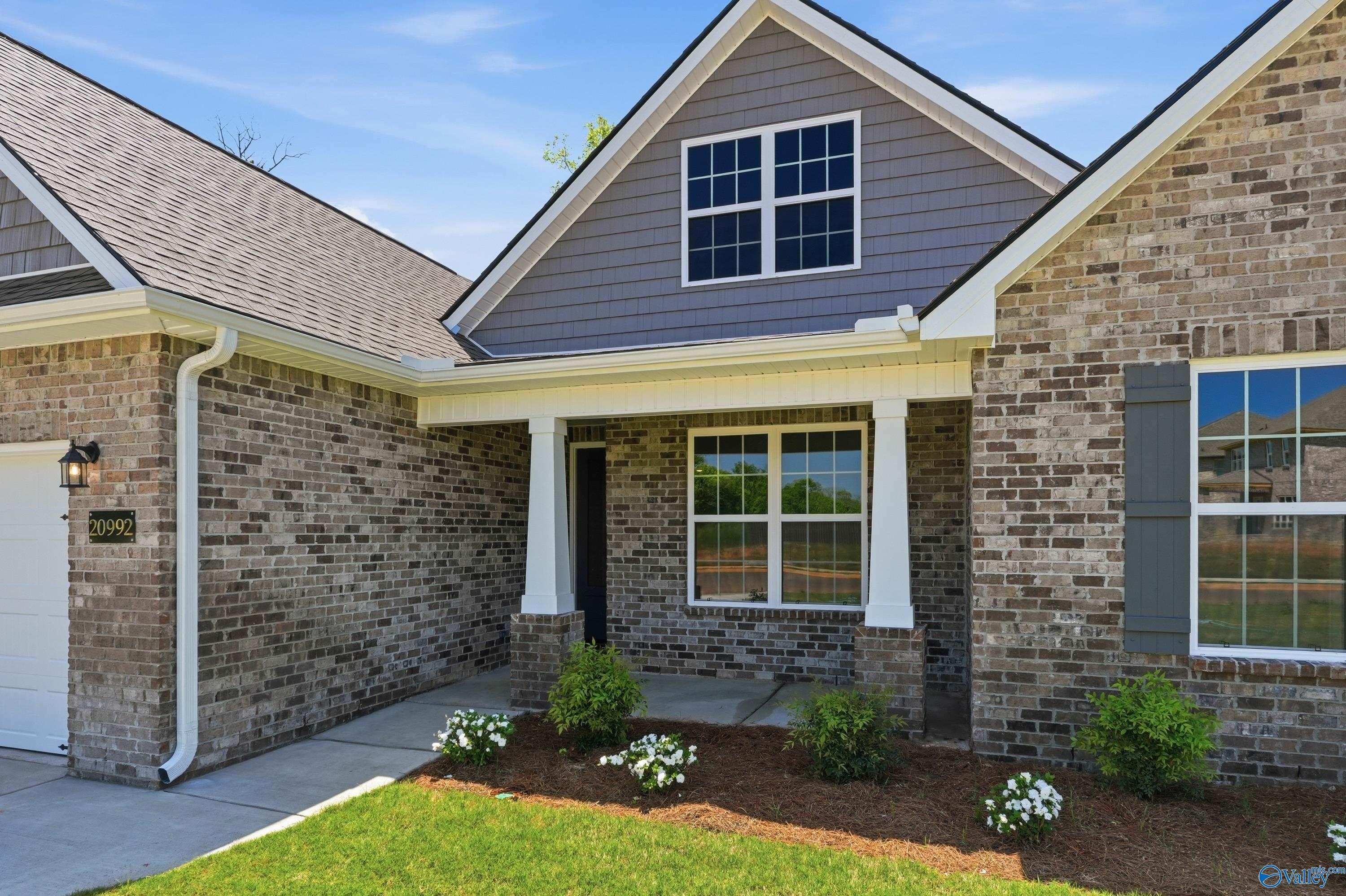Modern gray brick single-story home with covered front porch, 2-car garage, and lush landscaping in Davidson Homes The Rockford B, Athens Alabama