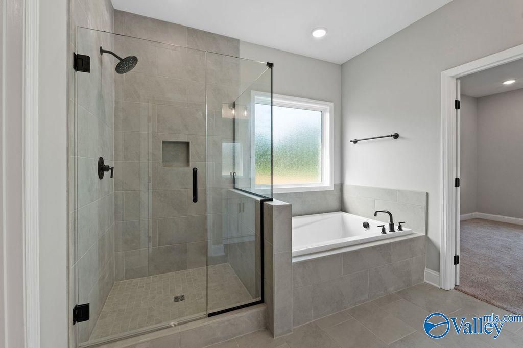Modern master bathroom featuring frameless glass shower, soaking tub, and gray tiles in Davidson Homes The Montgomery B, Hartselle, AL