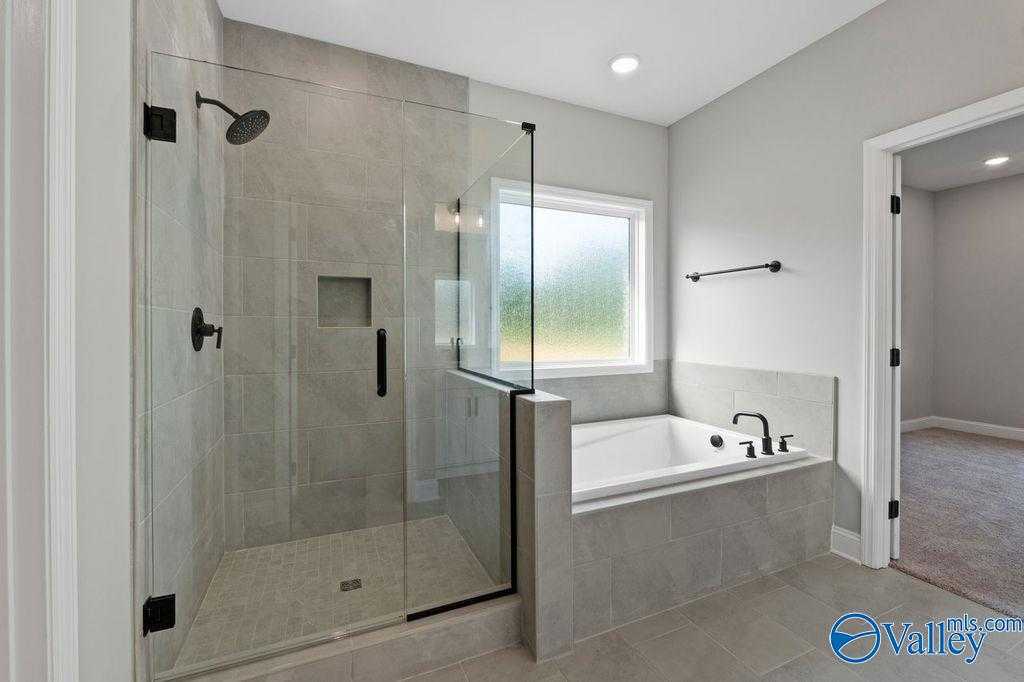 Modern master bathroom featuring frameless glass shower, soaking tub, and gray tiles in Davidson Homes The Montgomery B, Hartselle, AL