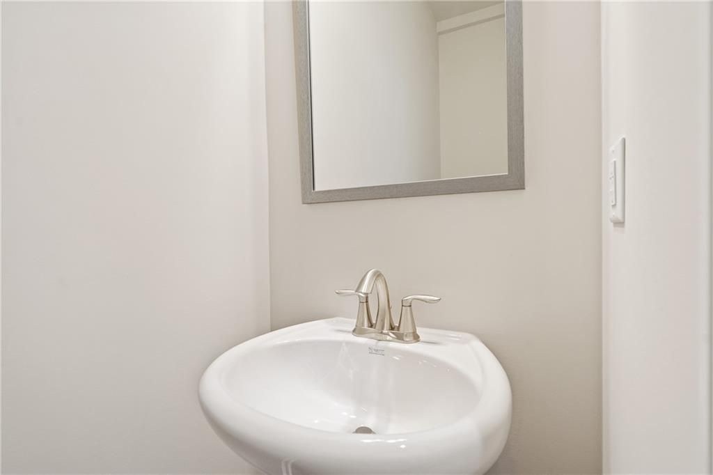 Elegant powder room featuring white pedestal sink and chrome faucet under framed mirror in Davidson Homes The Cary B, Kennesaw, Georgia