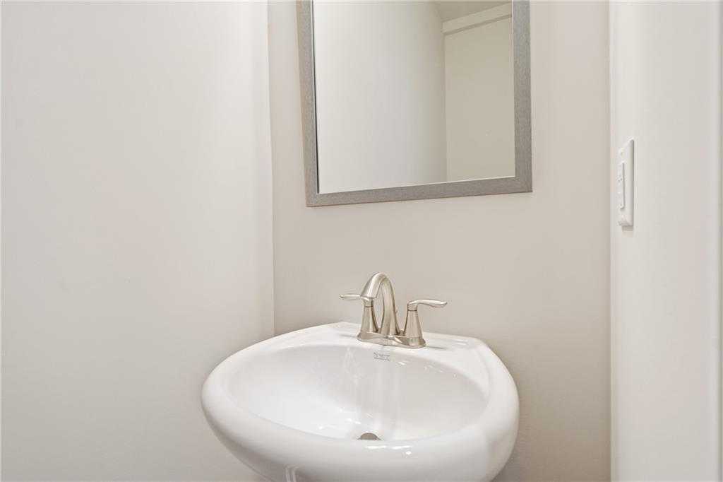 Elegant powder room with white pedestal sink, chrome faucet, and silver-framed mirror in Davidson Homes The Cary B, Kennesaw, Georgia