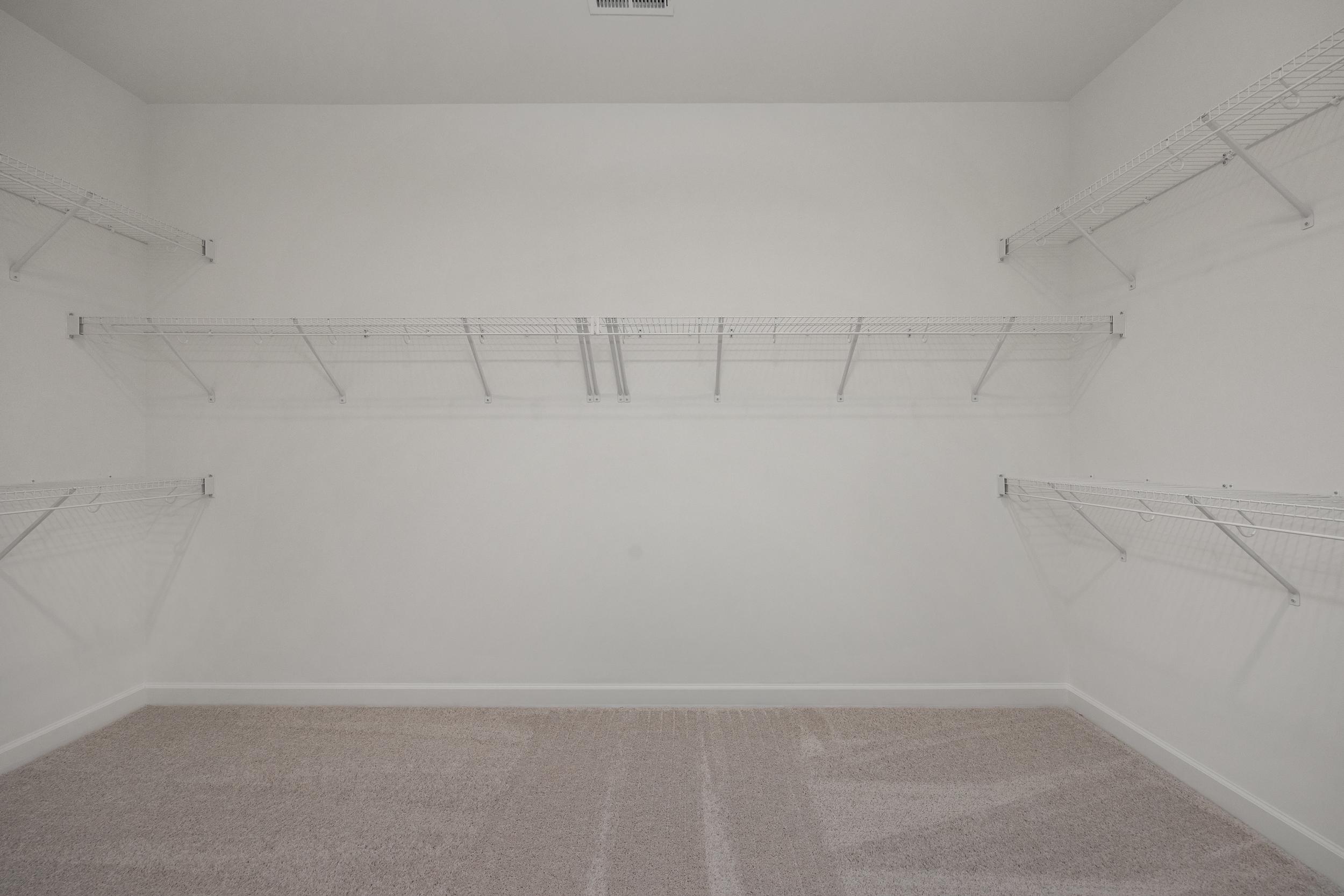 Spacious walk-in closet in The Hickory II master suite with white walls, wire shelving, and carpeted floor