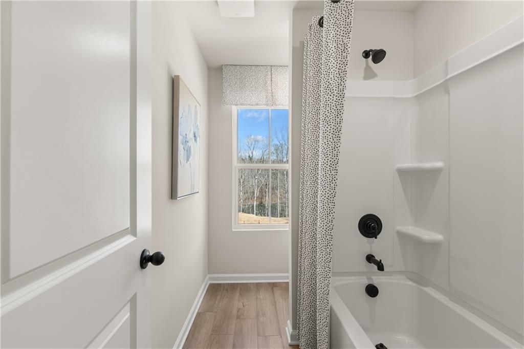 Bright bathroom with deep soaking tub, tiled shower, and window view in Davidson Homes The Burton C, Canton, Georgia