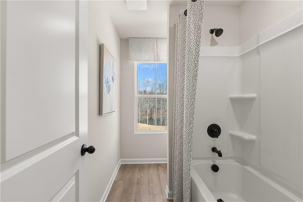 Bright bathroom with deep soaking tub, tiled shower, and window view in Davidson Homes The Burton C, Canton, Georgia