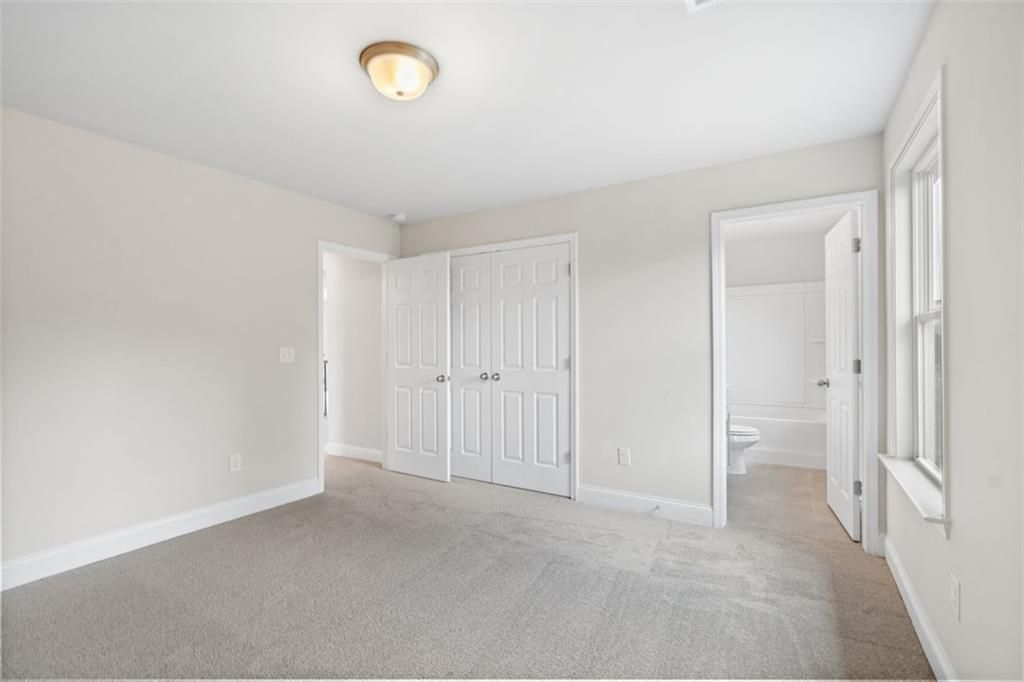 Spacious secondary bedroom with carpeted floors, double closet doors, and en-suite bathroom in Davidson Homes The Willow B, Hoschton, GA
