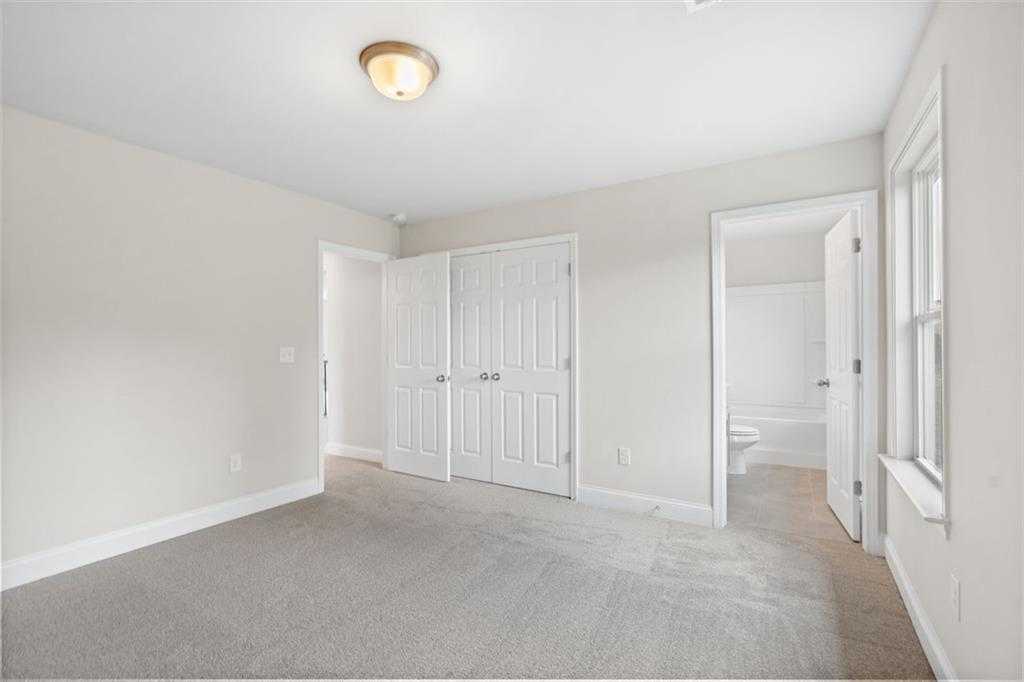 Spacious secondary bedroom with carpeted floors, double closet doors, and en-suite bathroom in Davidson Homes The Willow B, Hoschton, GA