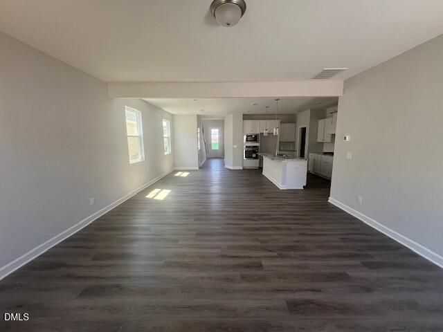 Open-concept great room with gray walls, hardwood floors, and adjacent white kitchen island in Davidson Homes The Adalynn A, Lillington, NC