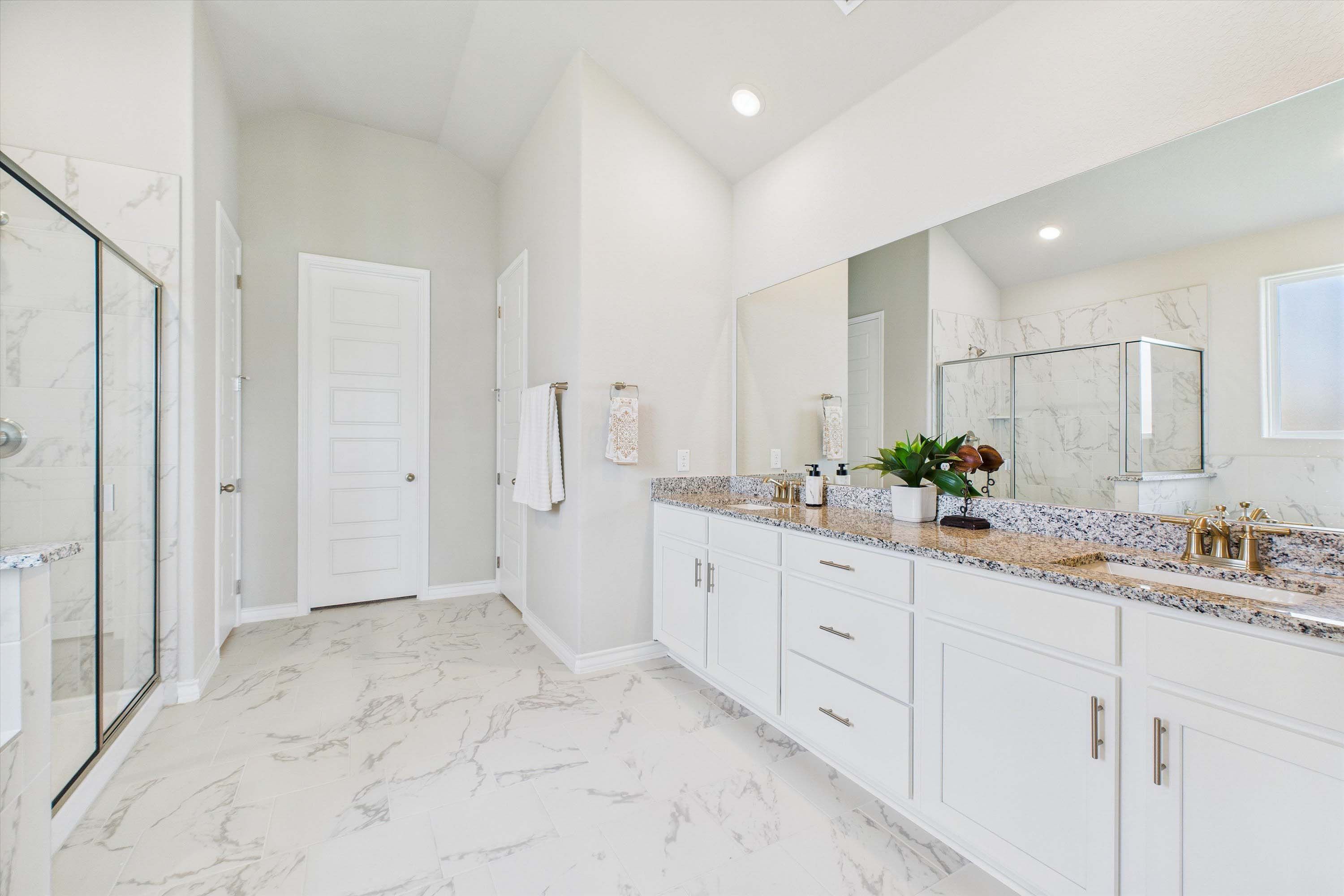 Spacious master bathroom in The Foster featuring dual vanity, granite countertops, and a walk-in glass shower.