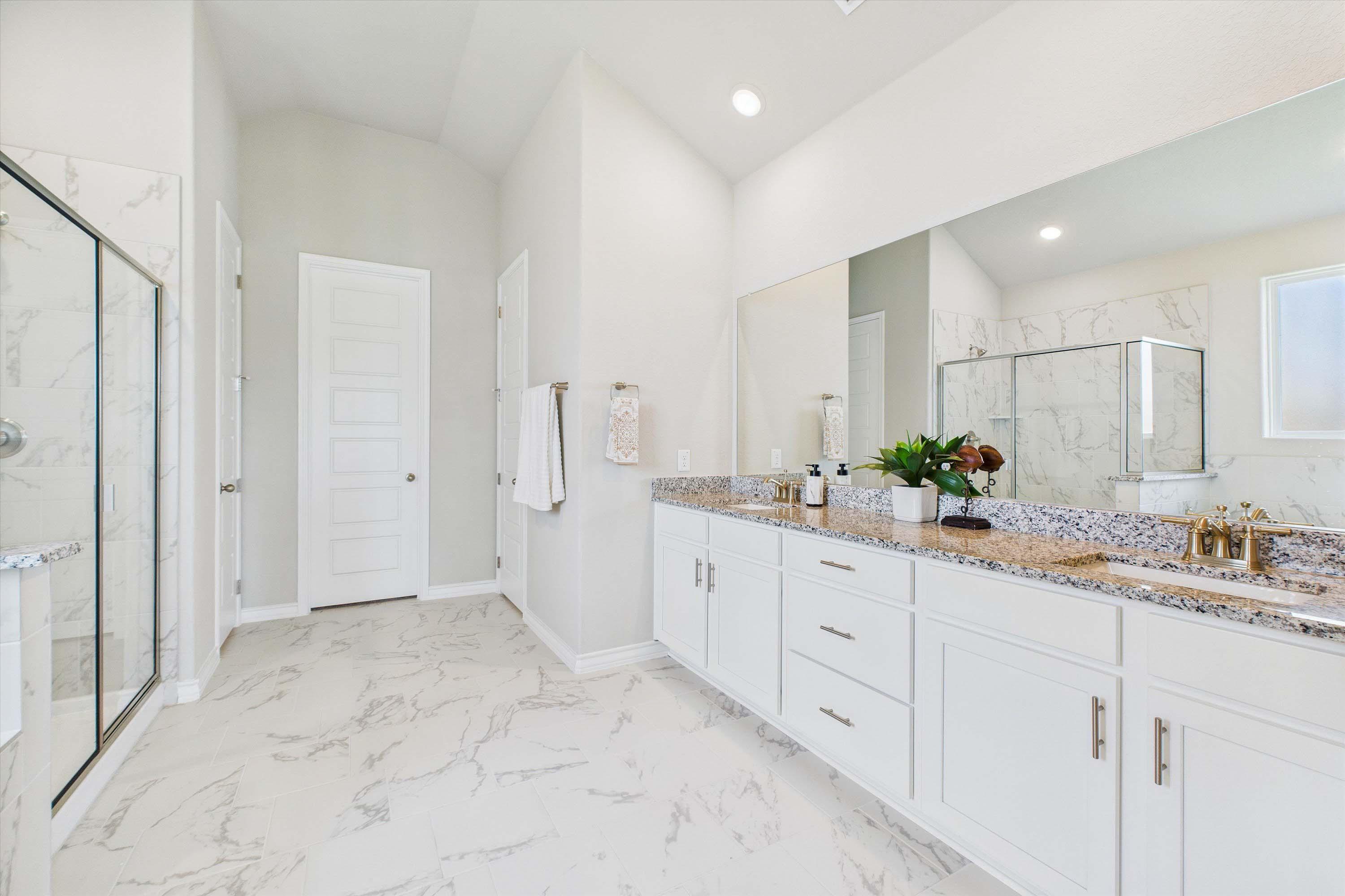 Spacious master bathroom in The Foster featuring dual vanity, granite countertops, and a walk-in glass shower.