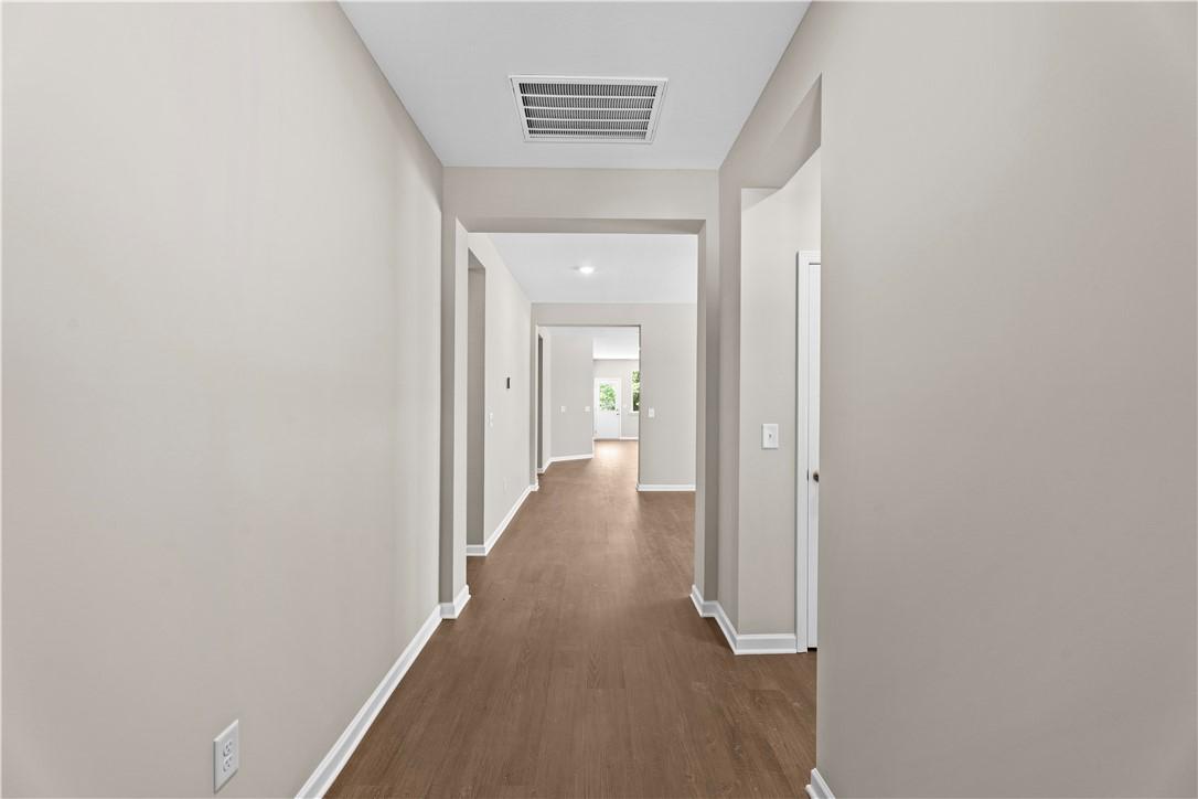 Bright hallway with hardwood floors and beige walls in The Orion 4-bedroom home by Evermore Homes, Cusseta, Alabama