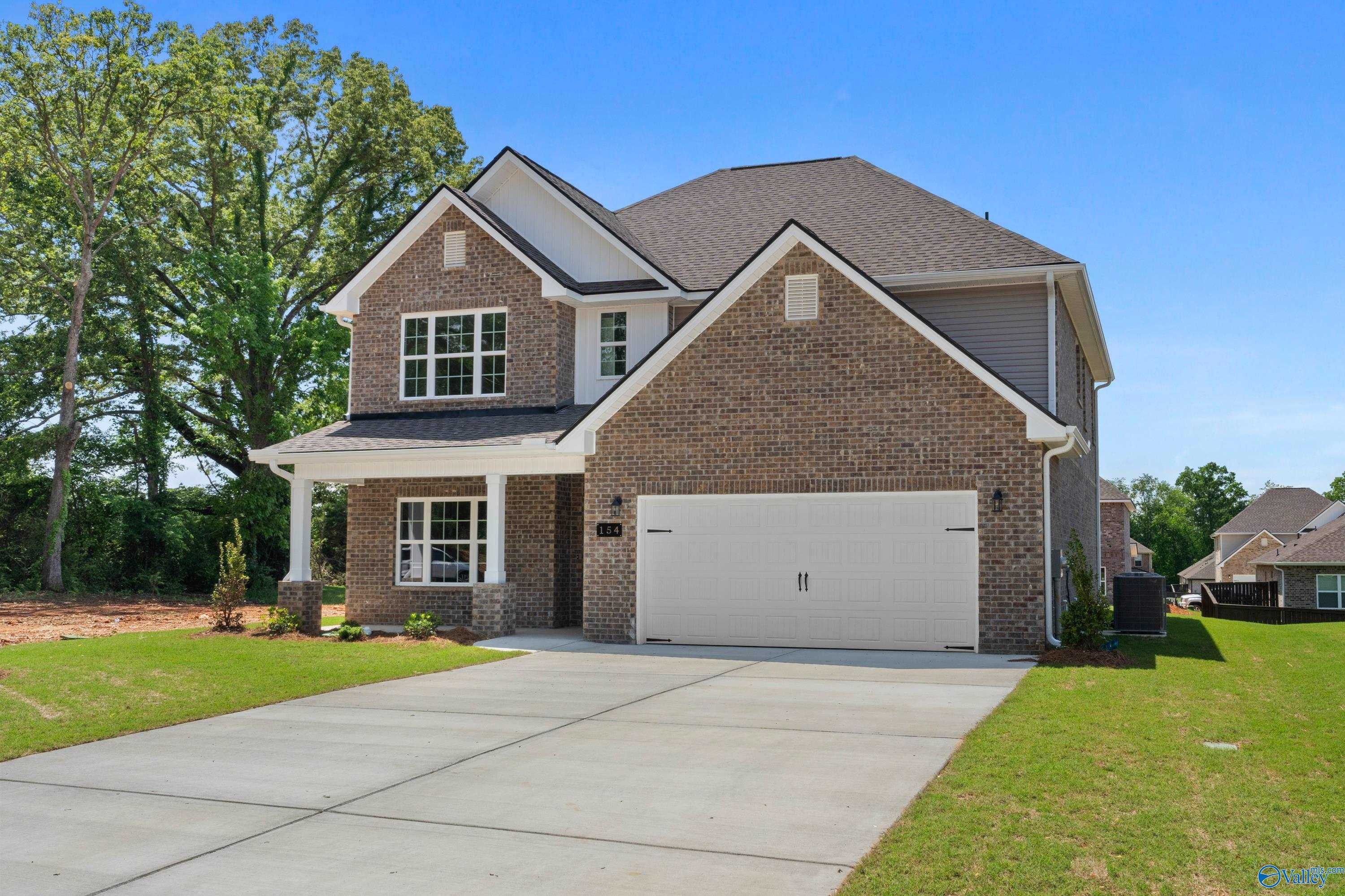 Two-story brick Davidson Homes Chelsea B with 2-car garage, front porch, and lush landscaping in Creek Grove, New Market, Alabama