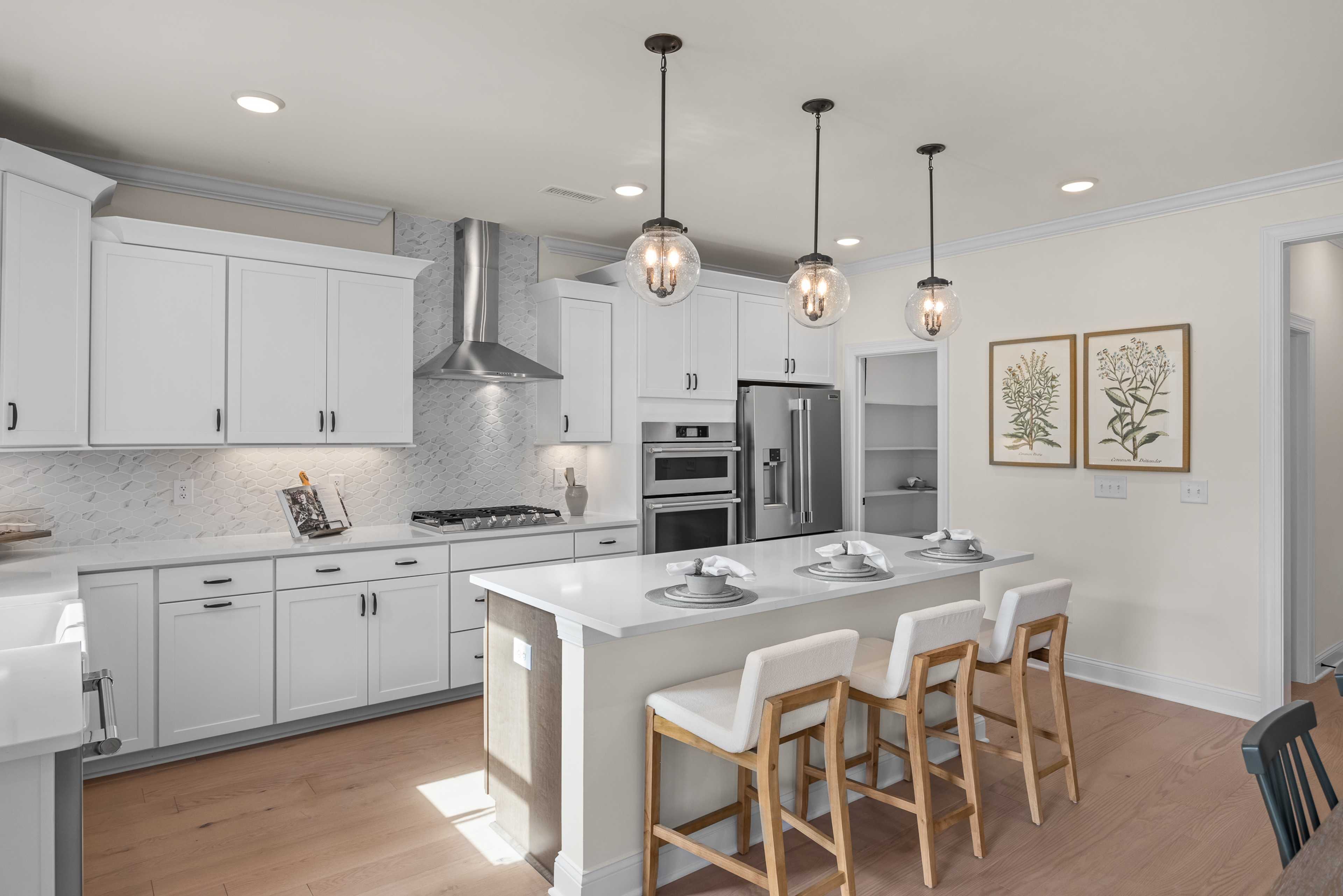 Spacious white shaker kitchen at Addison West in Holly Springs NC with quartz island, hardwood floors, and French doors