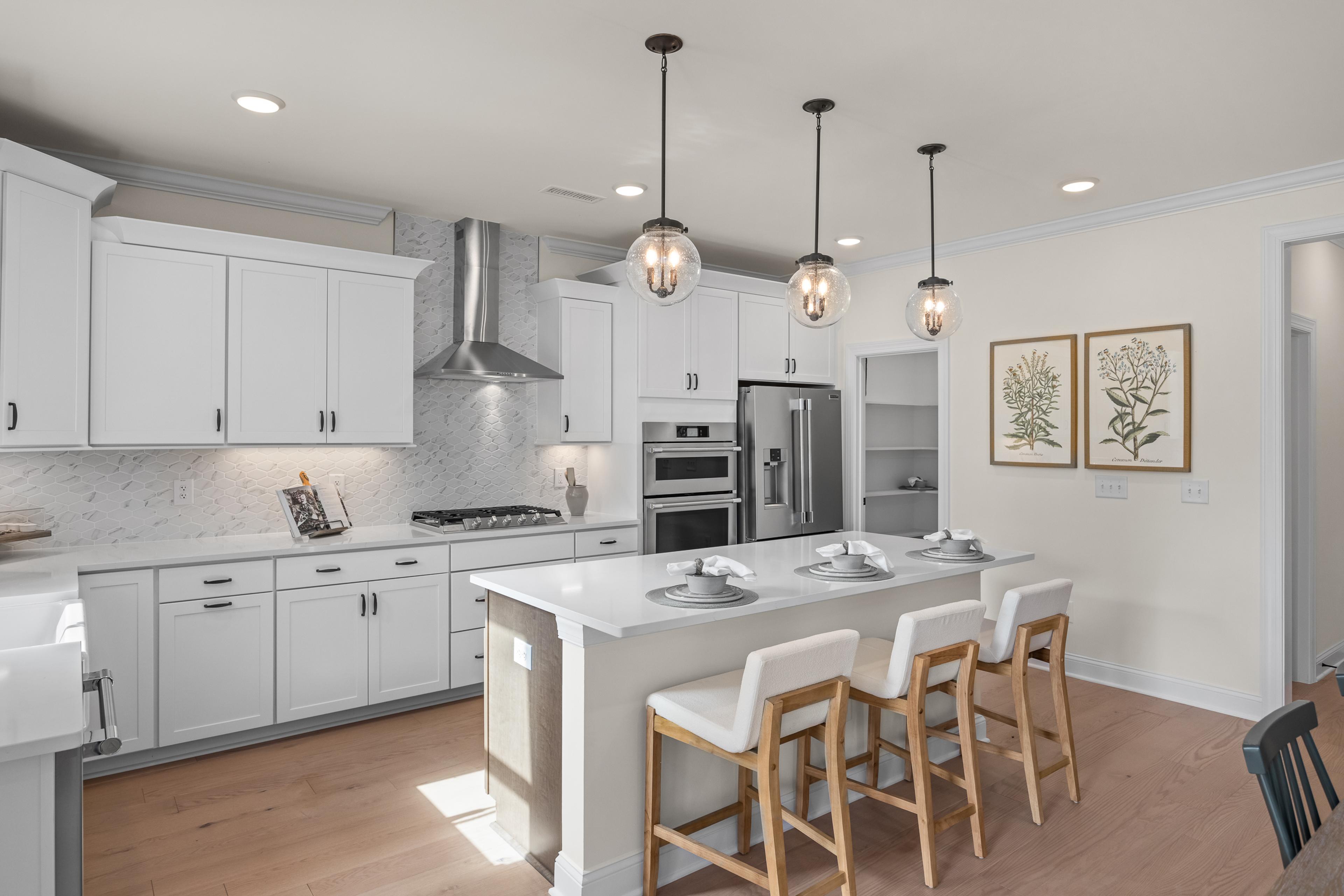 Spacious white shaker kitchen at Addison West in Holly Springs NC with quartz island, hardwood floors, and French doors