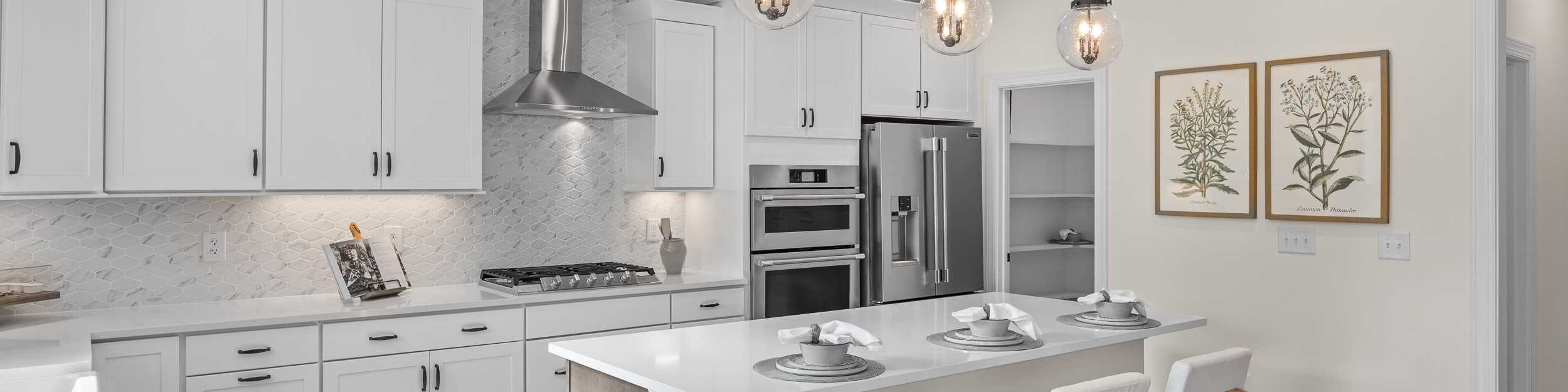 Spacious white shaker kitchen at Addison West in Holly Springs NC with quartz island, hardwood floors, and French doors