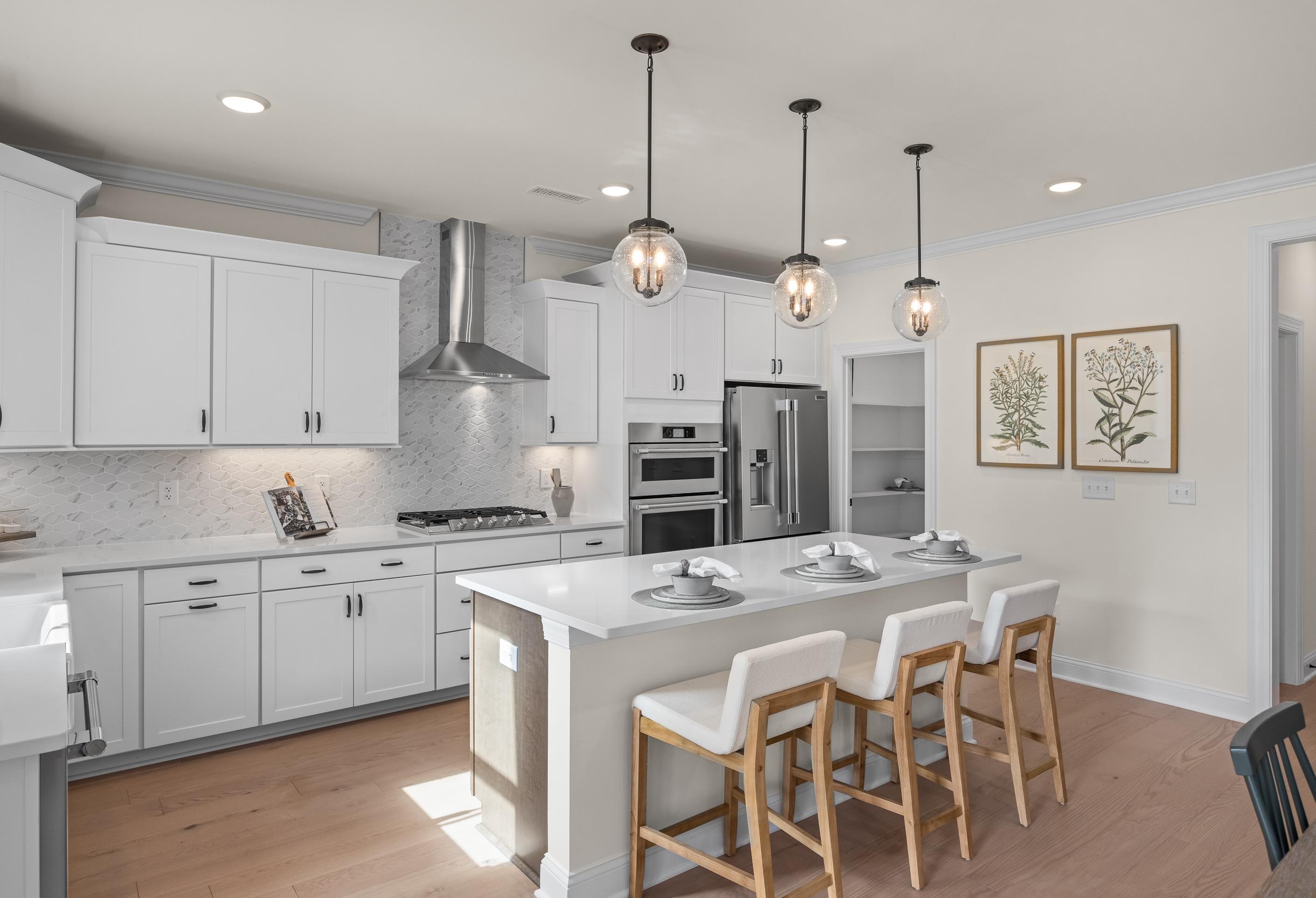 Spacious gourmet kitchen in The Crawford featuring white shaker cabinets, quartz island with bar stools, stainless appliances