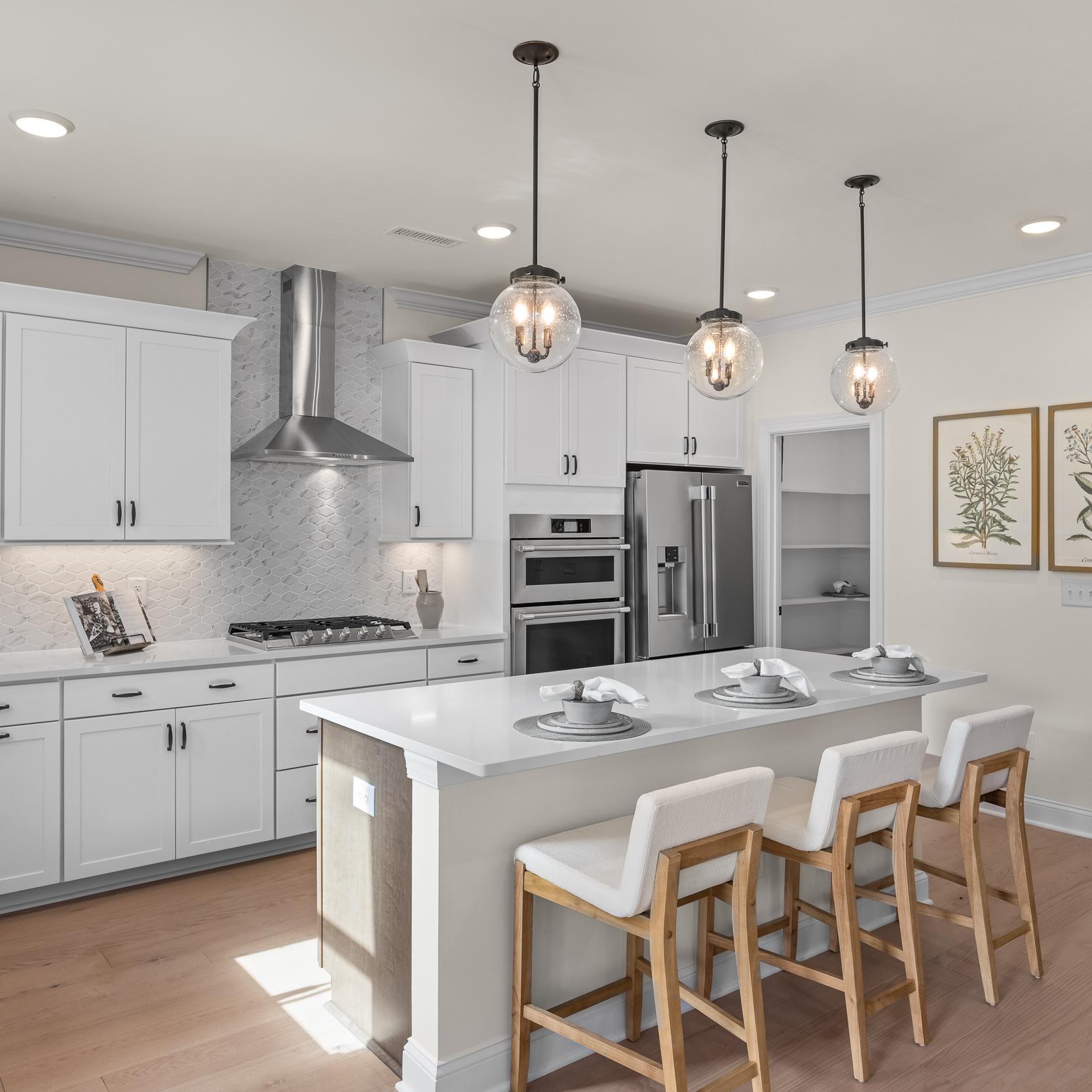 Modern white kitchen with island bar seating in Ashland, Apex NC by Davidson Homes, subway tile backsplash, hardwood floors