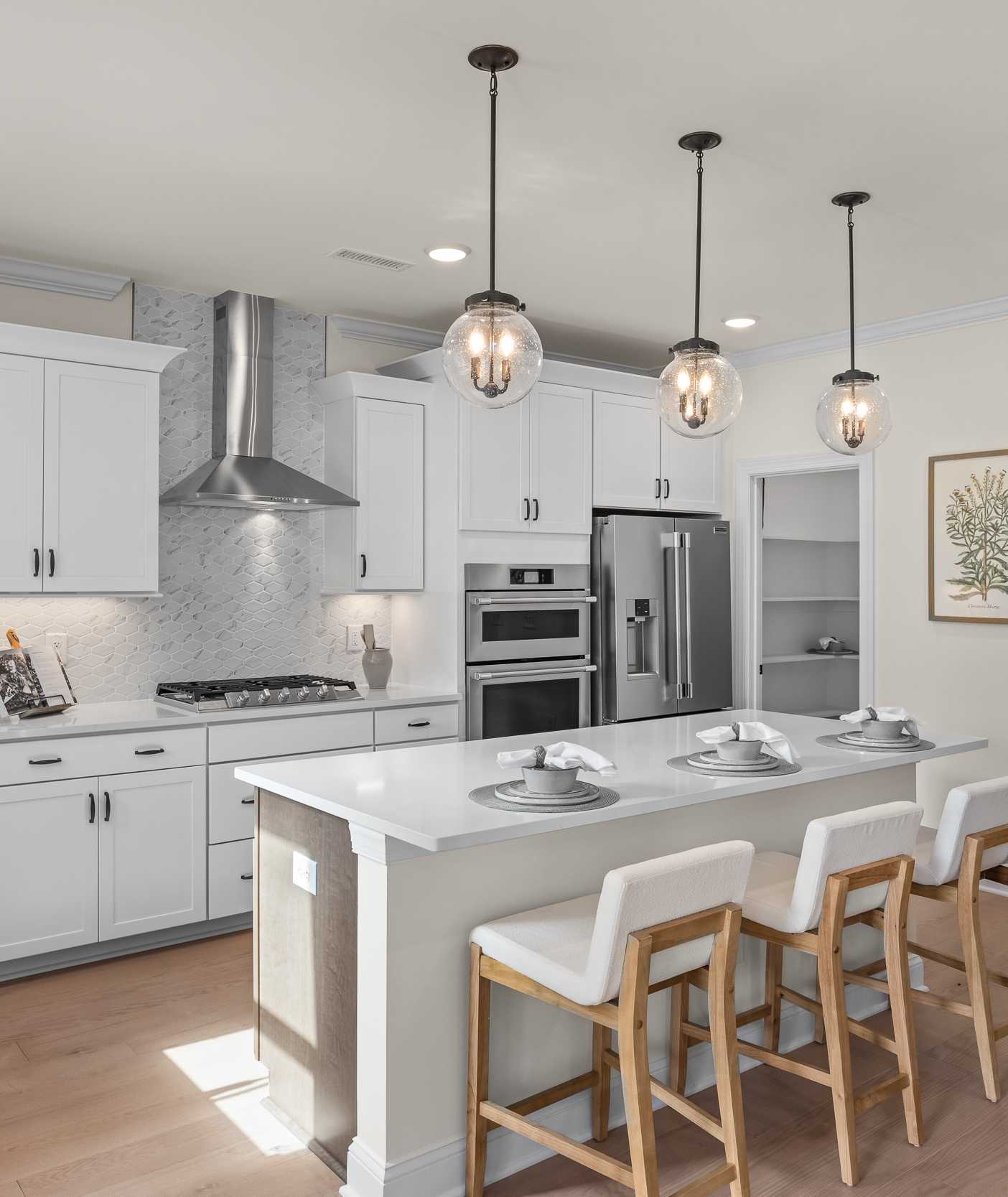 Spacious white shaker kitchen at Addison West in Holly Springs NC with quartz island, hardwood floors, and French doors