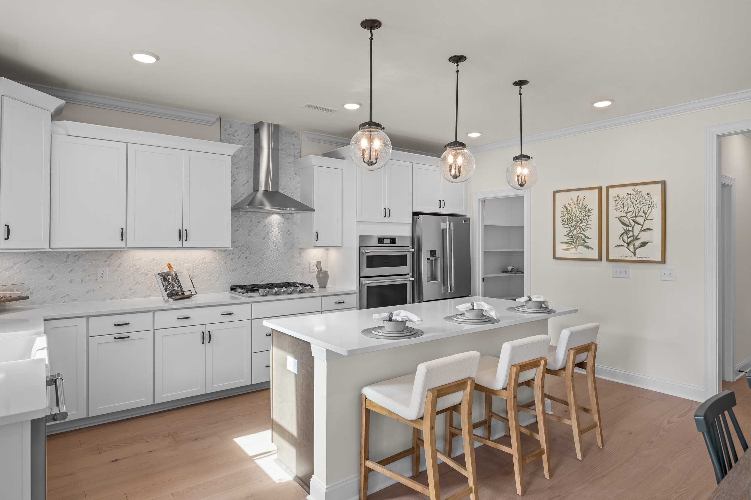 Spacious white shaker kitchen at Addison West in Holly Springs NC with quartz island, hardwood floors, and French doors