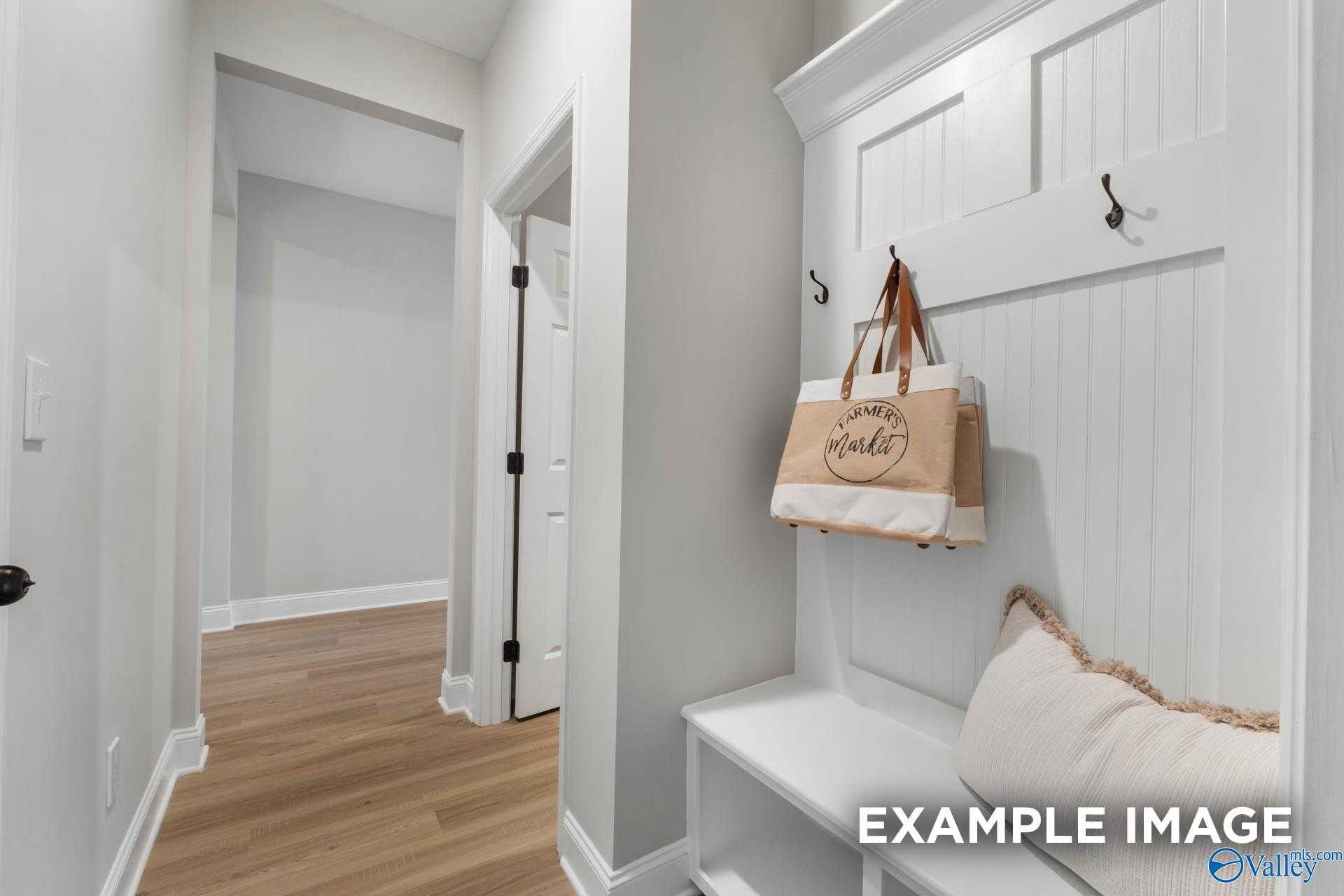 Charming entryway with white wainscoting, built-in bench, coat hooks, and hanging tote in Davidson Homes The Daphne C, Ramsay Cove, Alabama