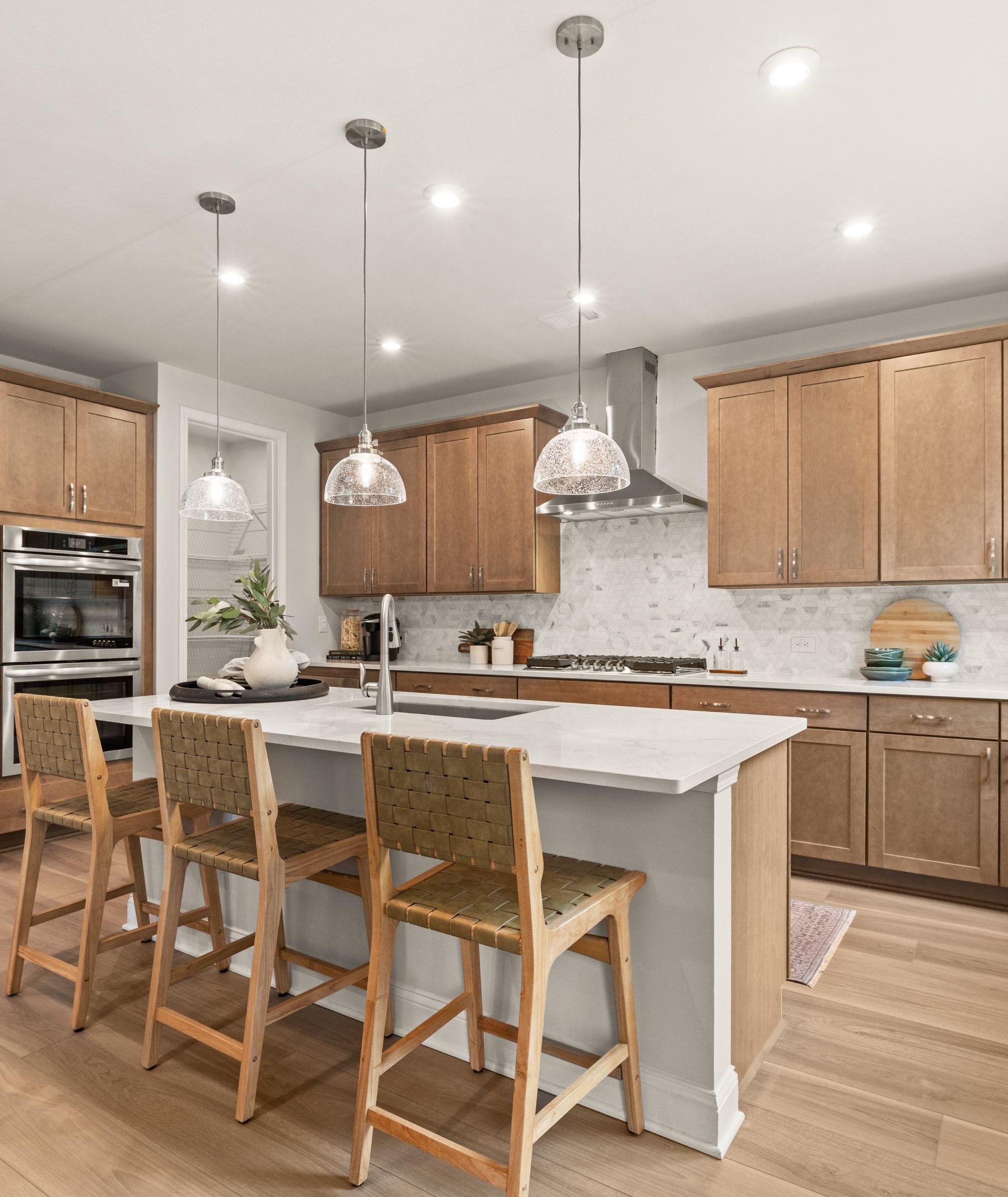 Modern kitchen at Lake Hollow in Gainesville, Georgia with island seating, wood cabinets, stainless appliances, and hardwood floors