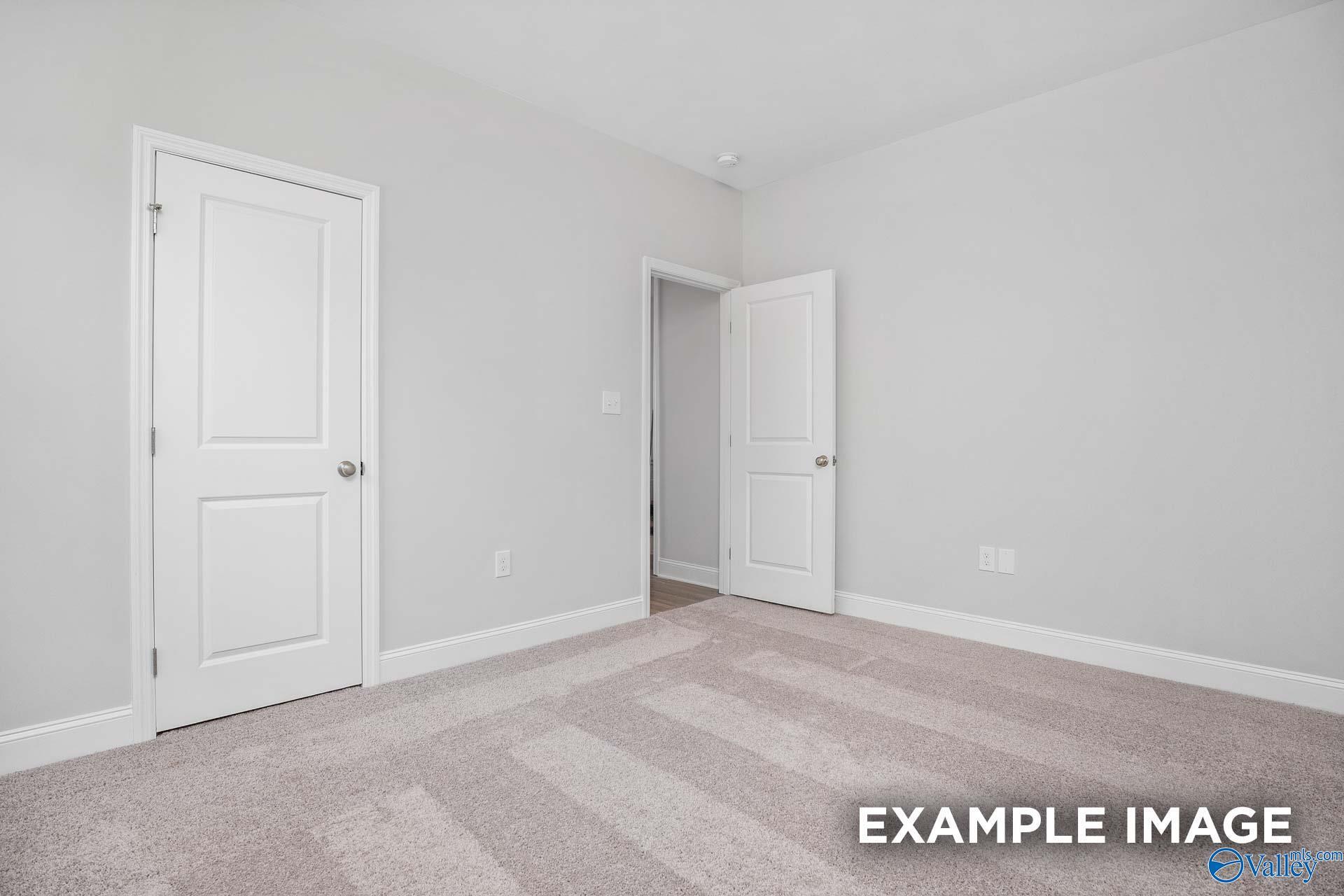Neutral bedroom with light gray walls, white doors, and beige carpet in The Daphne D 4-bedroom home, Meridianville, Alabama