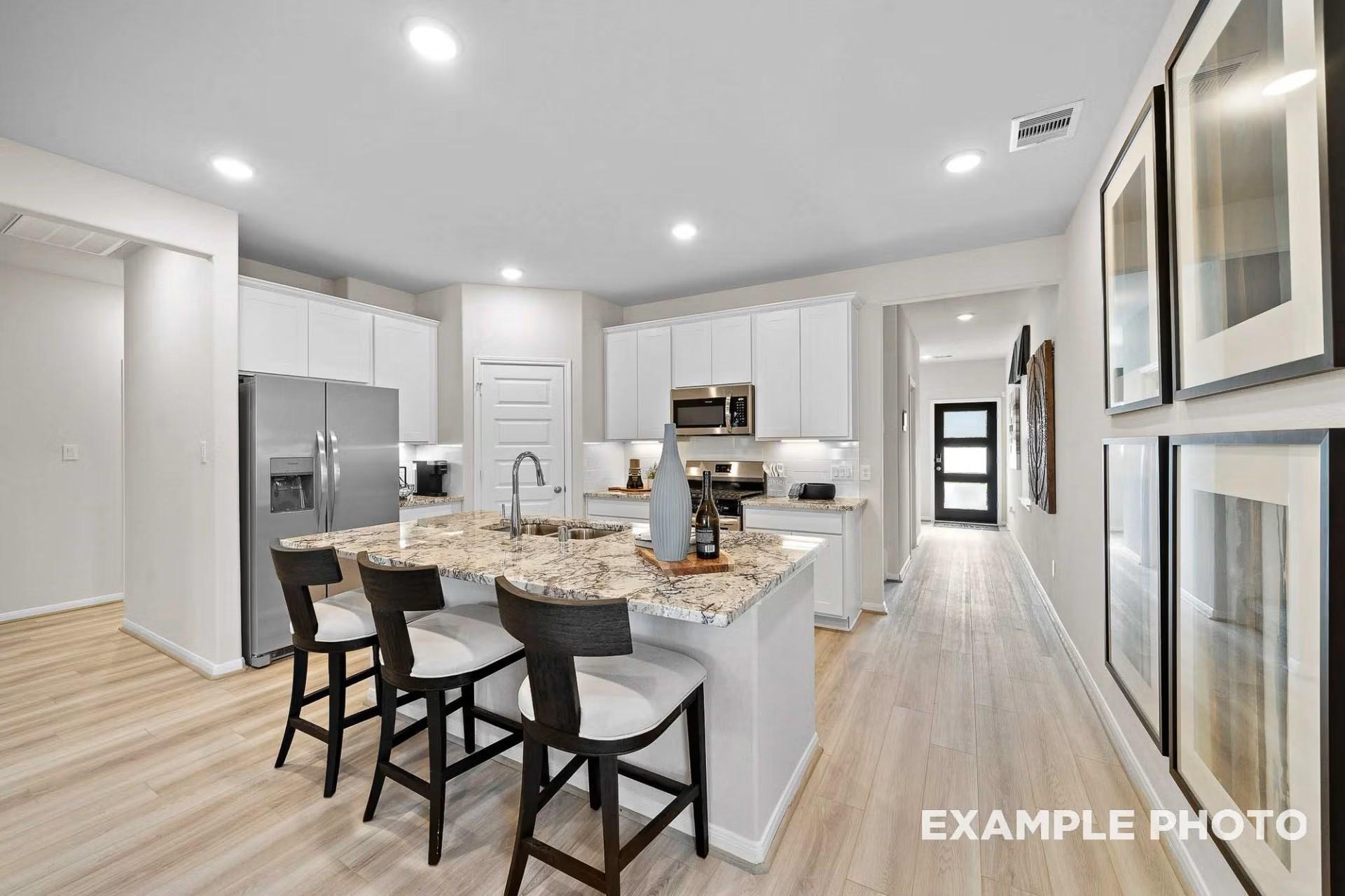 Modern kitchen with granite island, white cabinets, and stainless appliances in Heartland, Texas Davidson Homes floor plan.